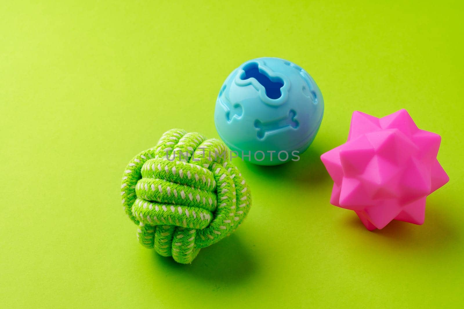 Colorful pet toys balls on green background close up