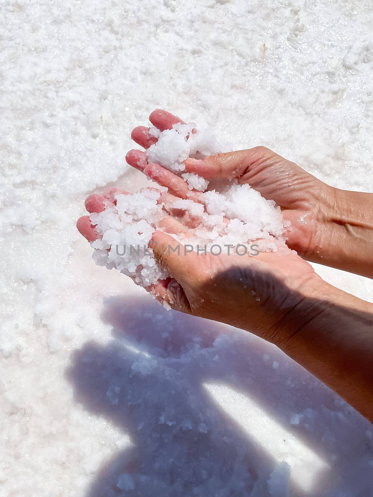 Womans hands with salt in her hands against the backdrop of salt lake. High quality photo