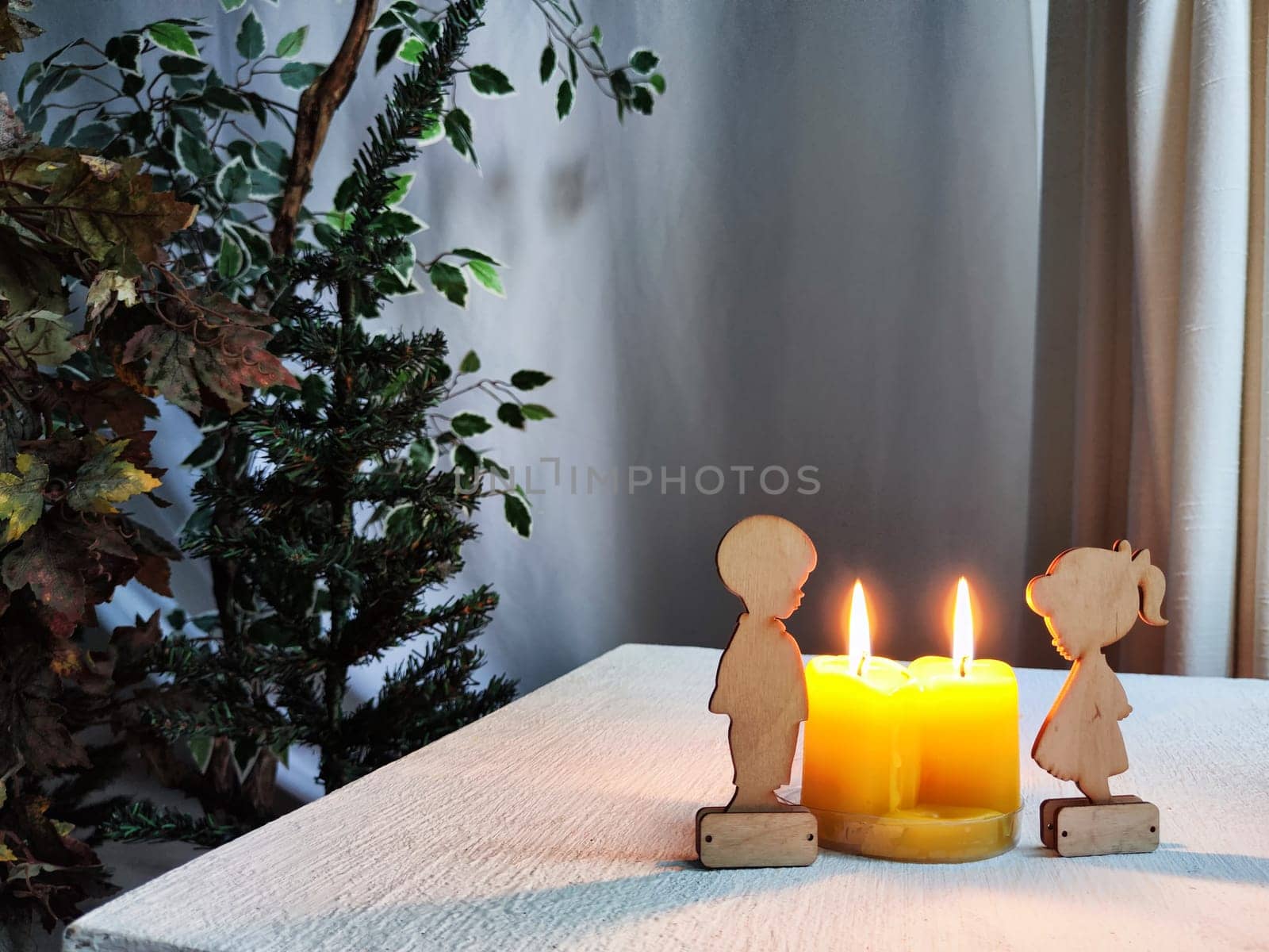 Wooden toys of boy and girl with yellow candles. Couple in love on Valentine's Day. Celebration of love and friendship. Card, background