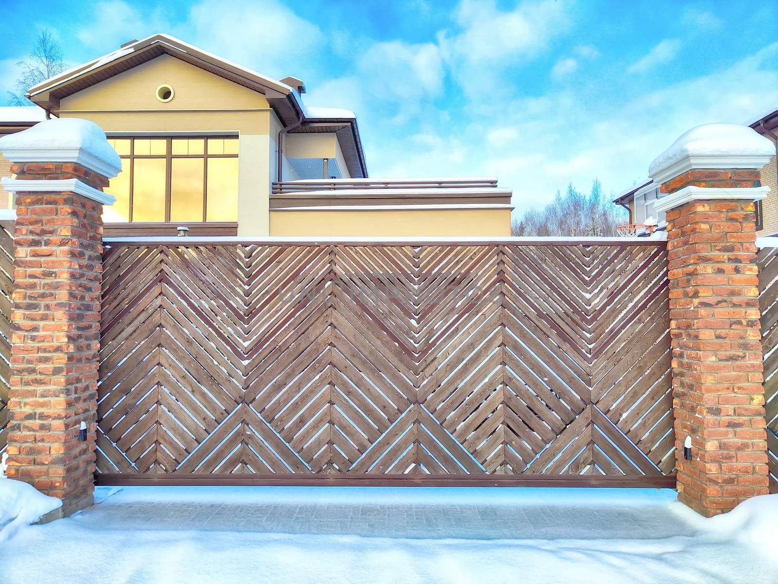 New gates to the private territory on winter day and snow. Wooden texture and background