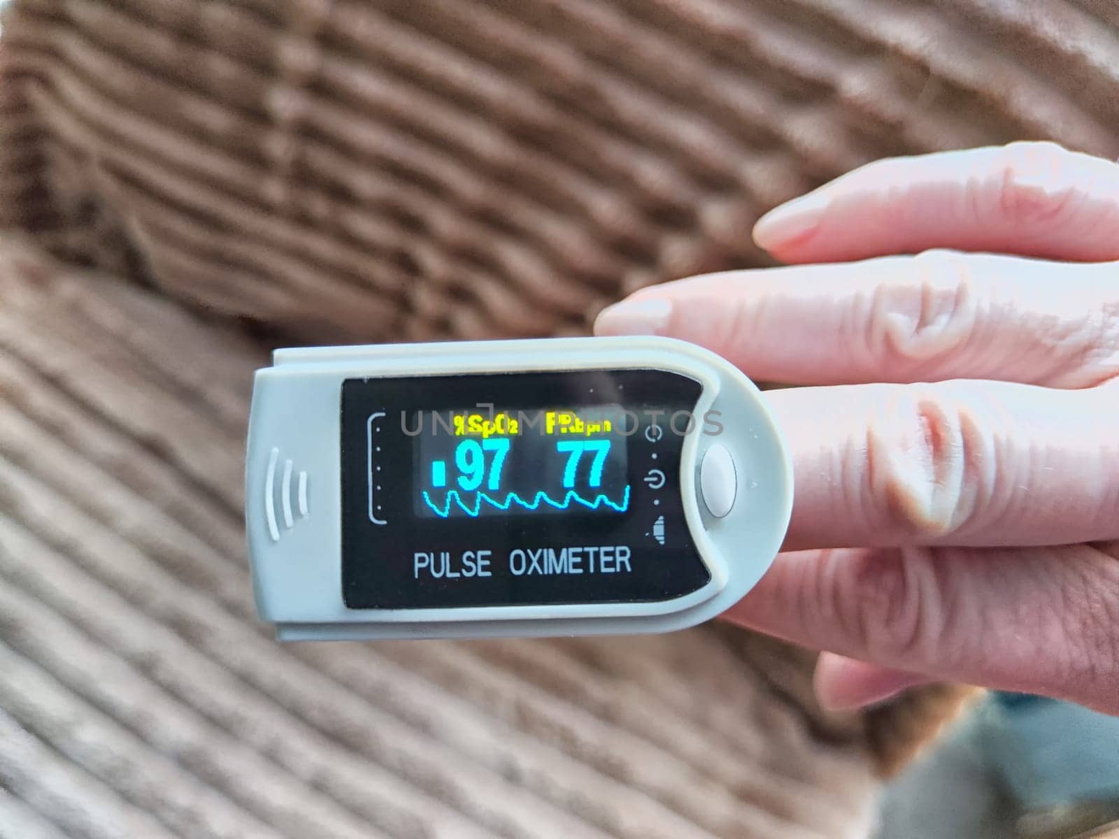 Close up of hand with a pulse oximeter on the finger.