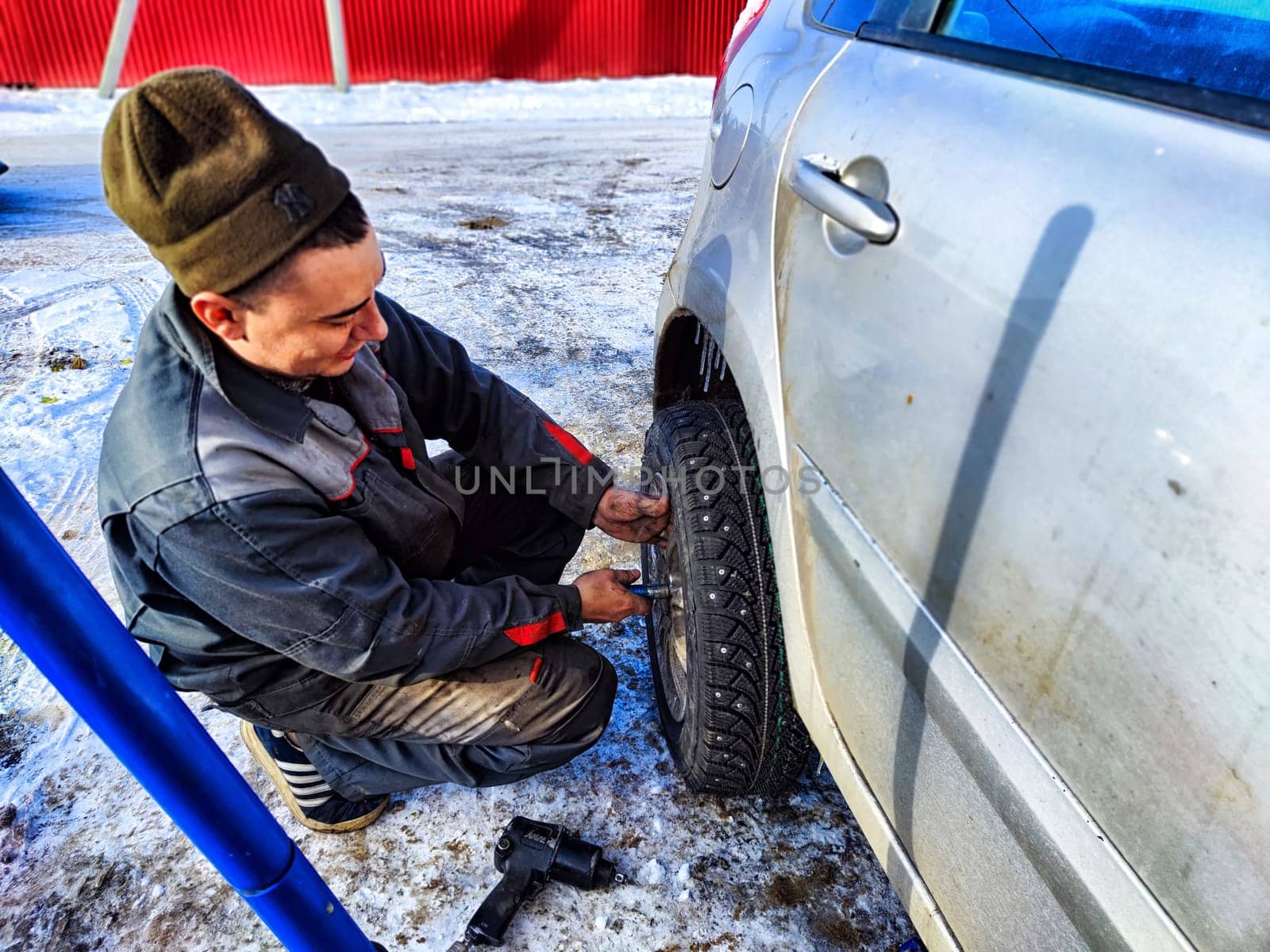 Ishim, Russia - November 27, 2023: man makes tire of car wheel before cold snow season. Experienced mechanic changes wheel of car. The driver prepares a classic car for driving in the snow in winter