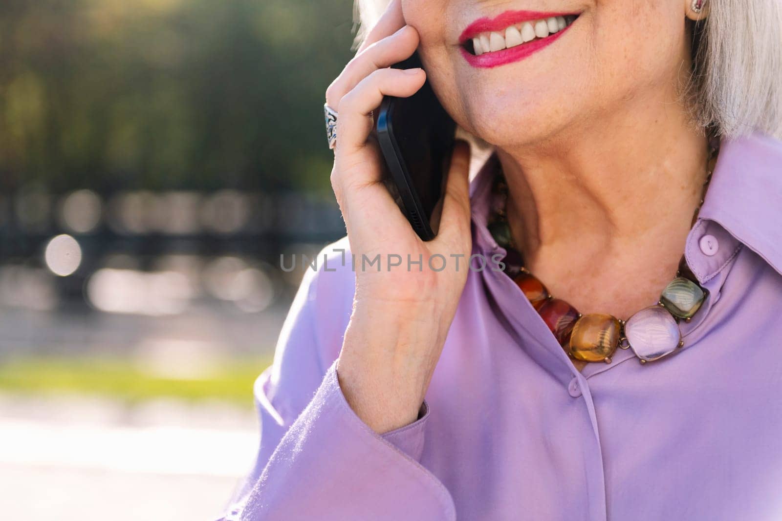 unrecognizable senior woman smiling happy talking by mobile phone outdoors, concept of technology and elderly people leisure, copy space for text