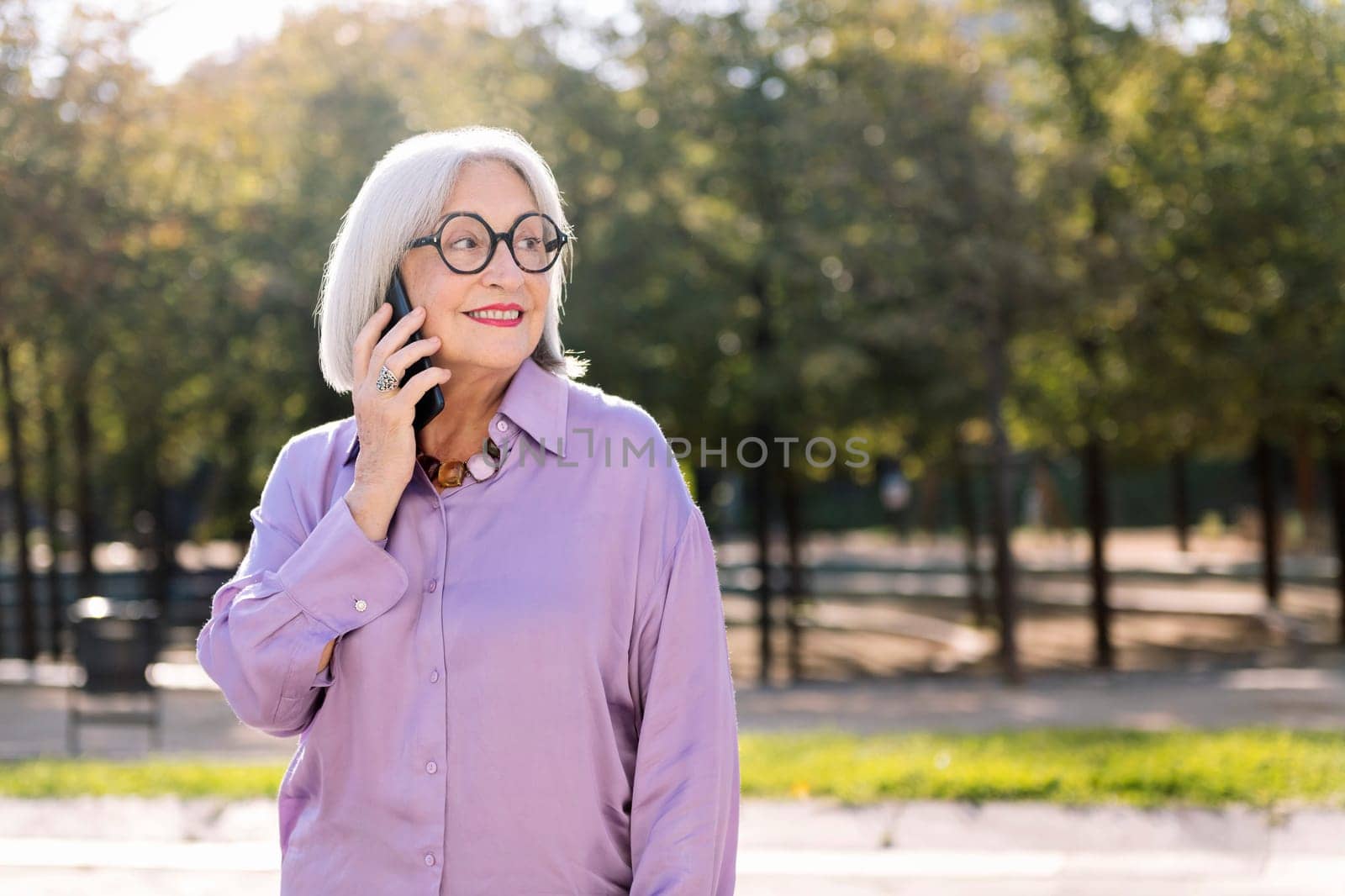 senior woman smiling happy talking by mobile phone outdoors, concept of technology and elderly people leisure, copy space for text