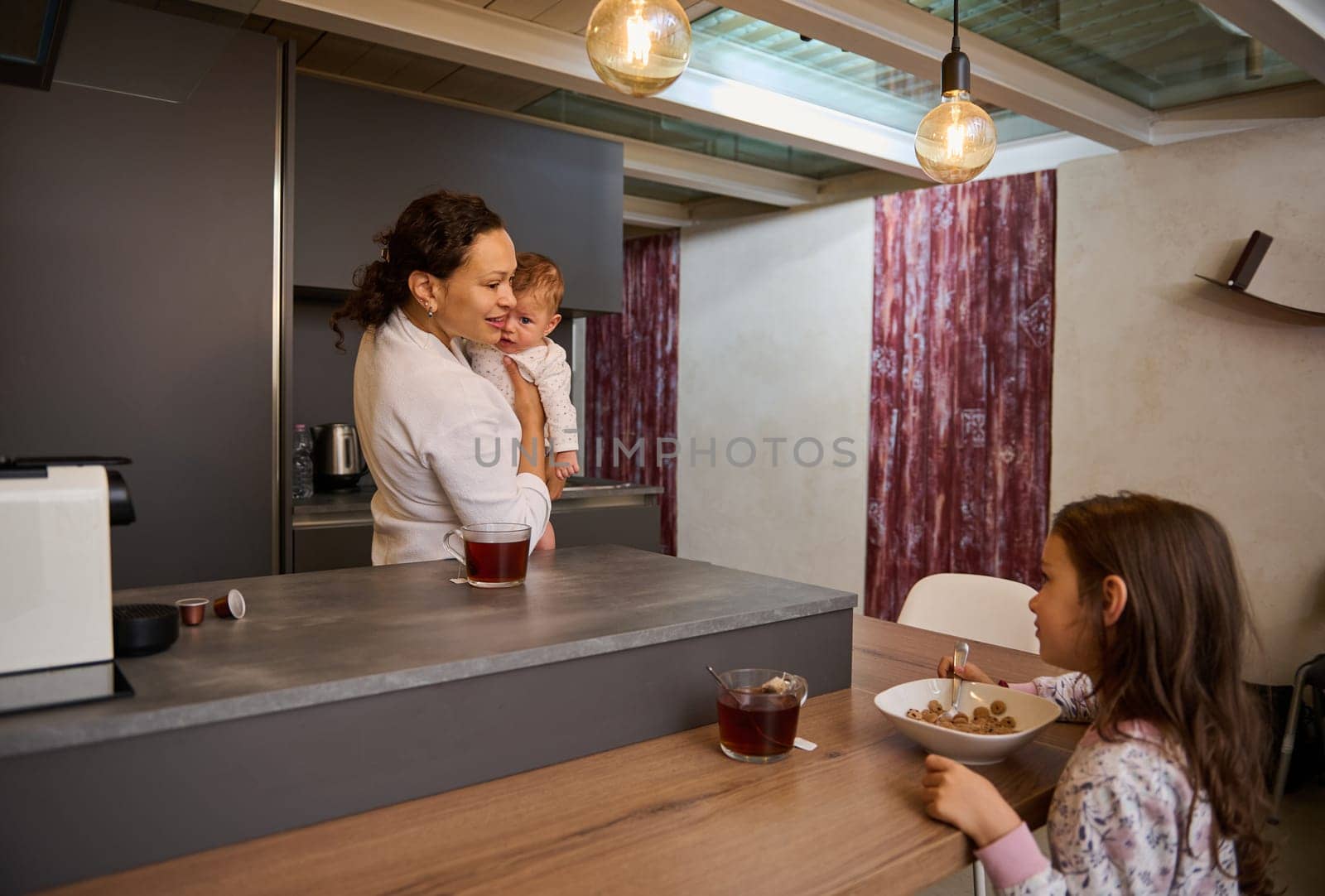 Portrait of a happy family, a single mother with two kids during breakfast in the morning at home kitchen by artgf