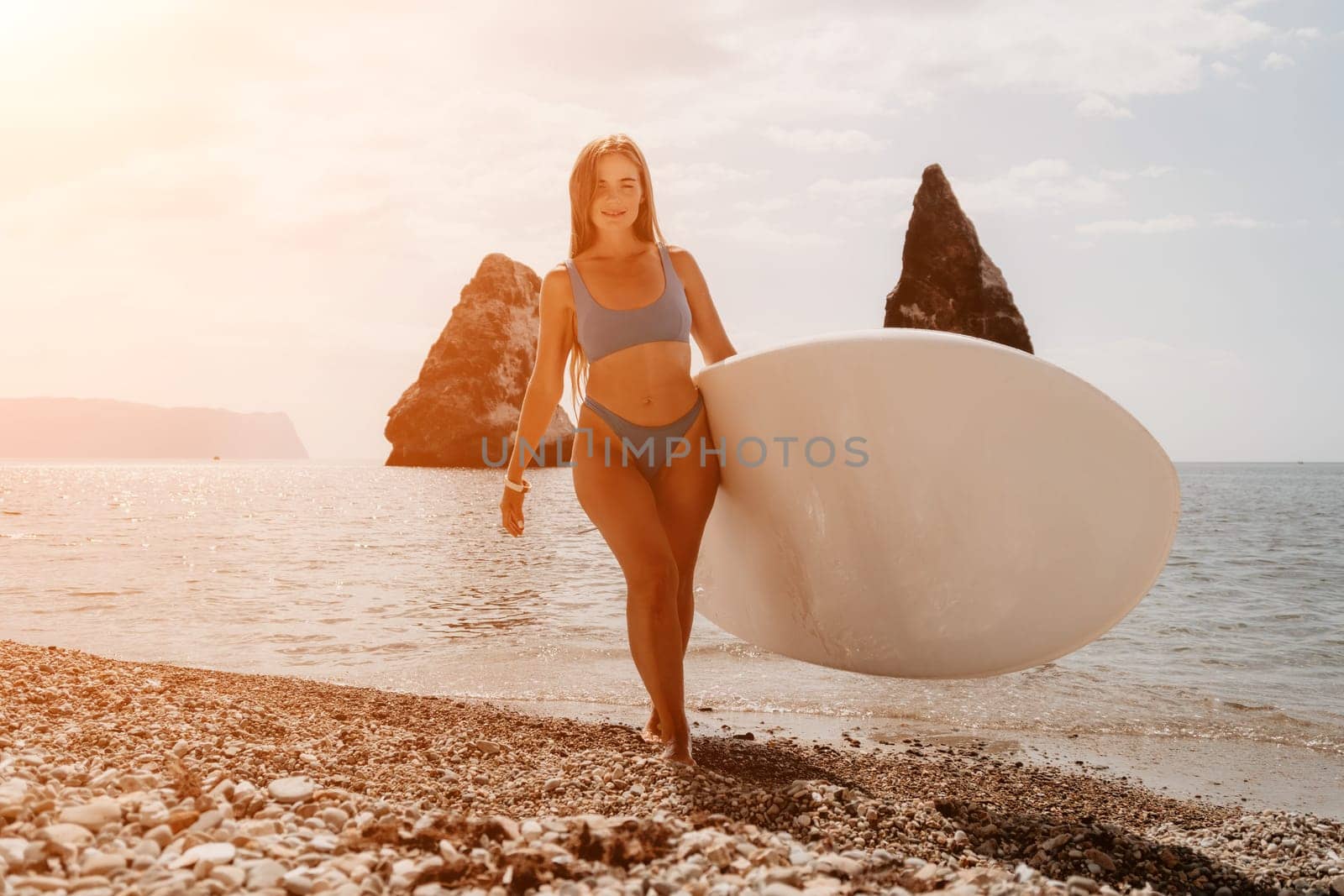 Close up shot of beautiful young caucasian woman with black hair and freckles looking at camera and smiling. Cute woman portrait in a pink bikini posing on a volcanic rock high above the sea