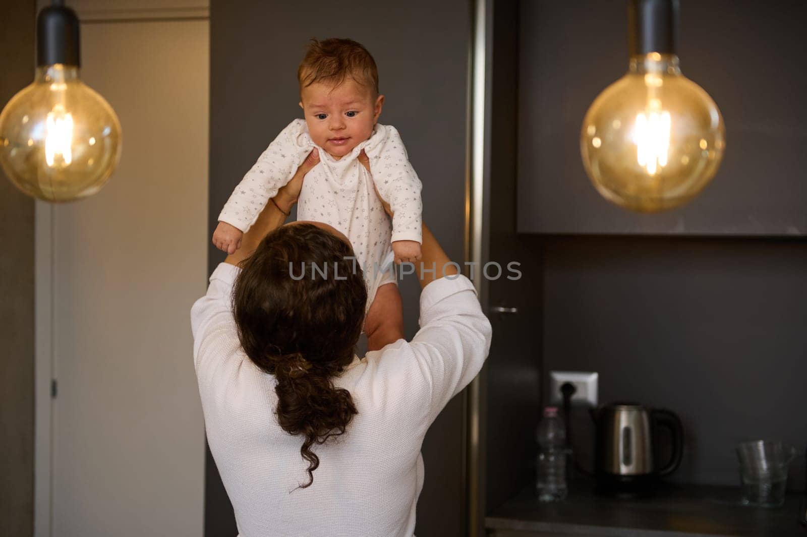 Loving mom caring of her newborn baby boy, enjoying playing together in a cozy home. Parent and little kid relaxing at home. Mother and son. Family having fun together. Childcare, maternity concept.