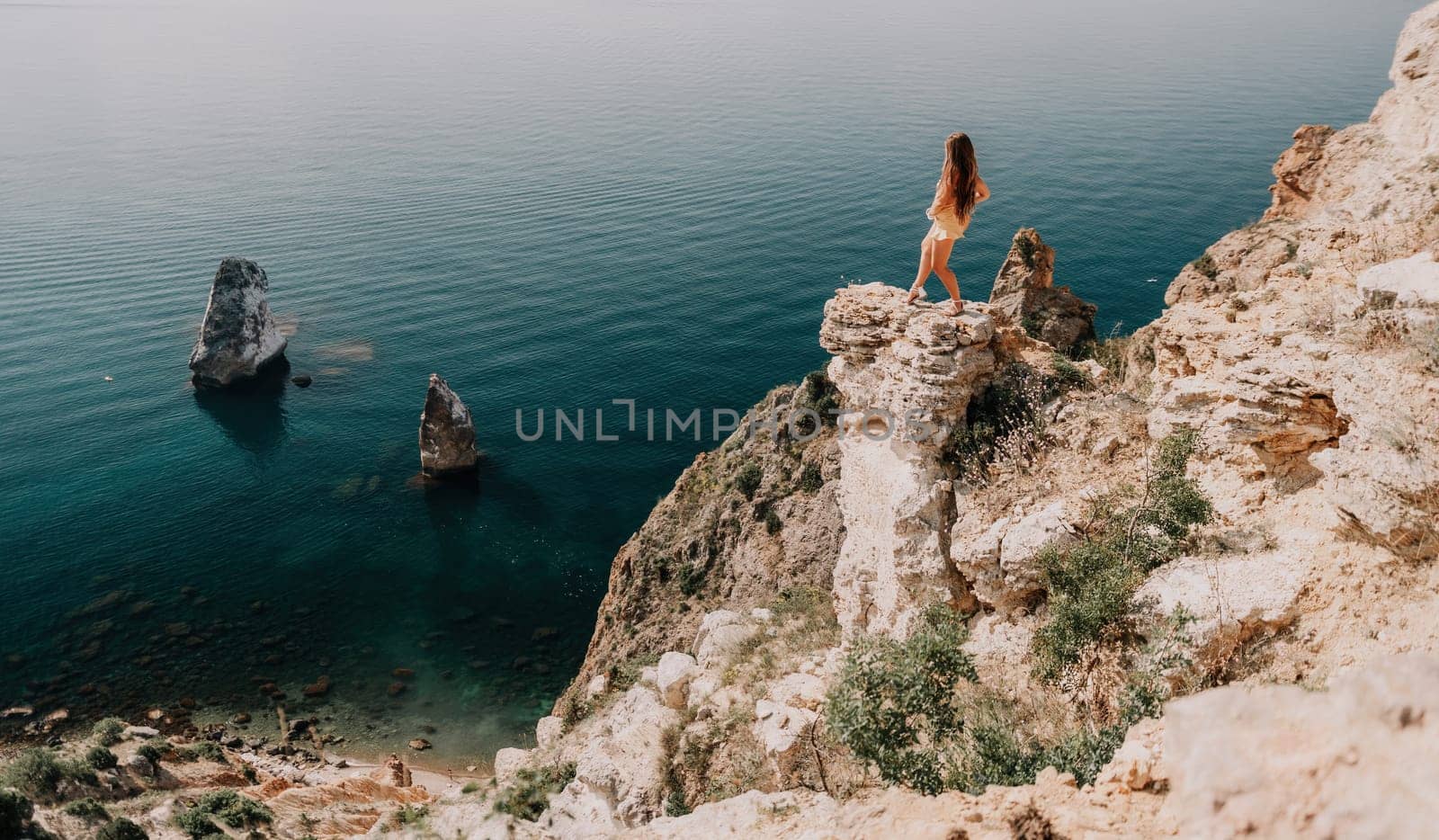 Woman travel sea. Happy tourist enjoy taking picture outdoors for memories. Woman traveler looks at the edge of the cliff on the sea bay of mountains, sharing travel adventure journey by panophotograph