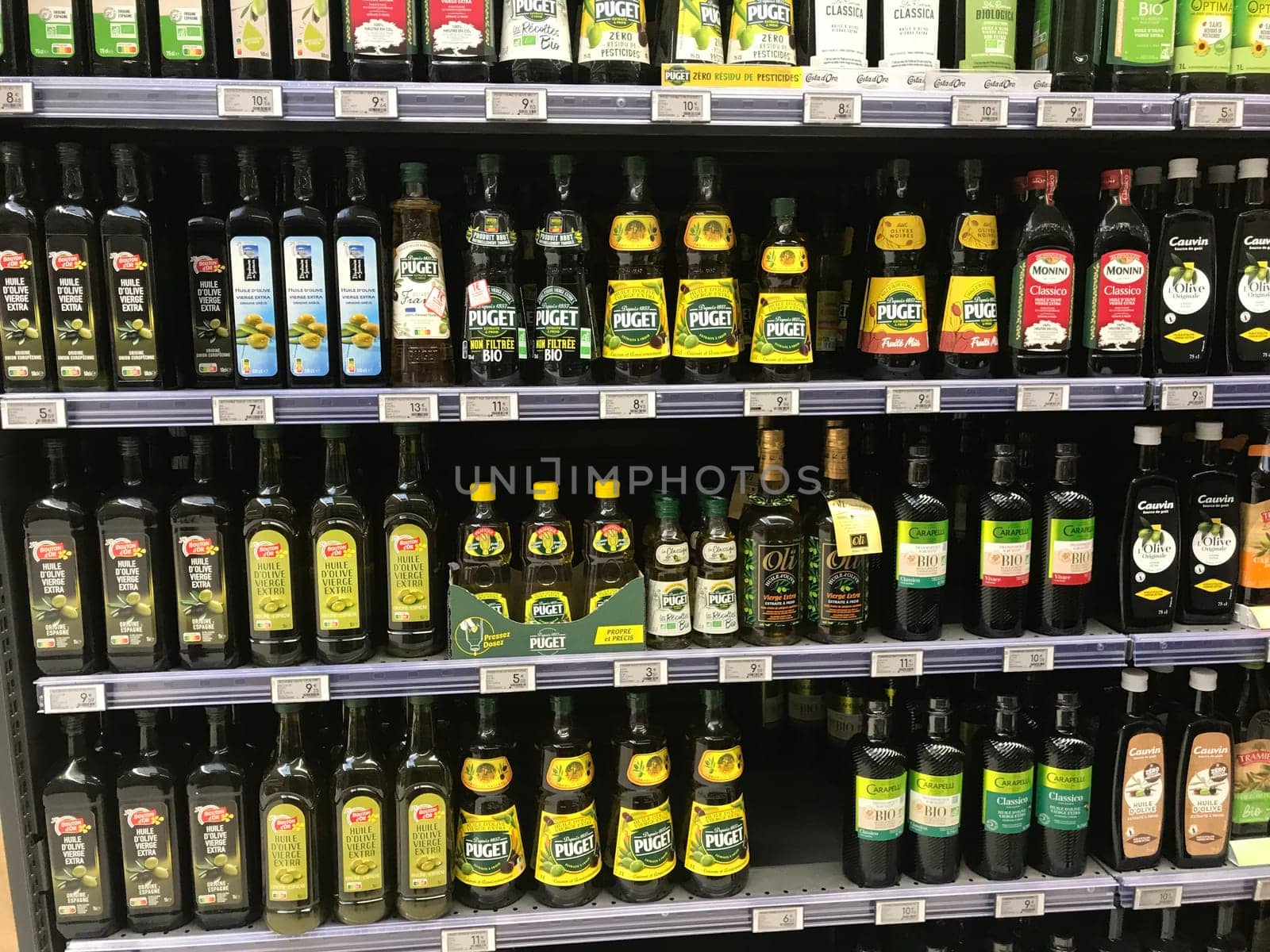 FRANCE, BORDEAUX, February, 2, 2024: Shelving for a large stock virgin olive oil bottles for sale at supermarket by FreeProd