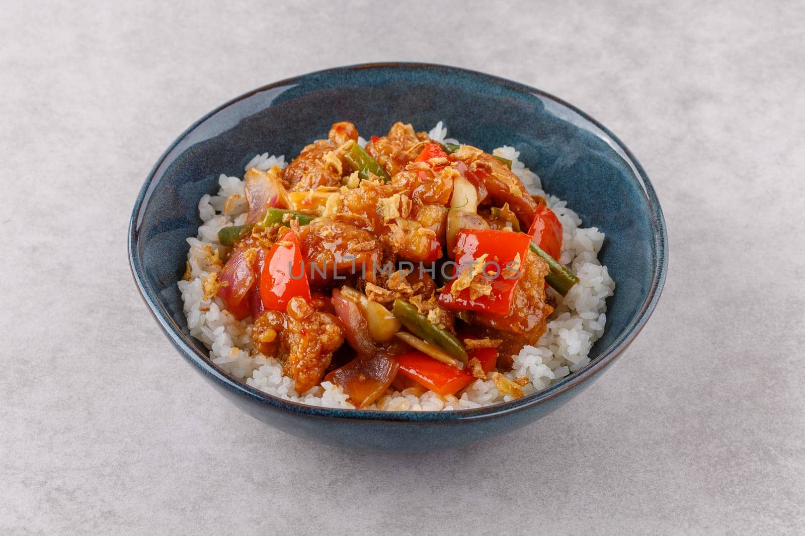 Chicken with rice in sweet and sour sauce on a stone background, studio shooting