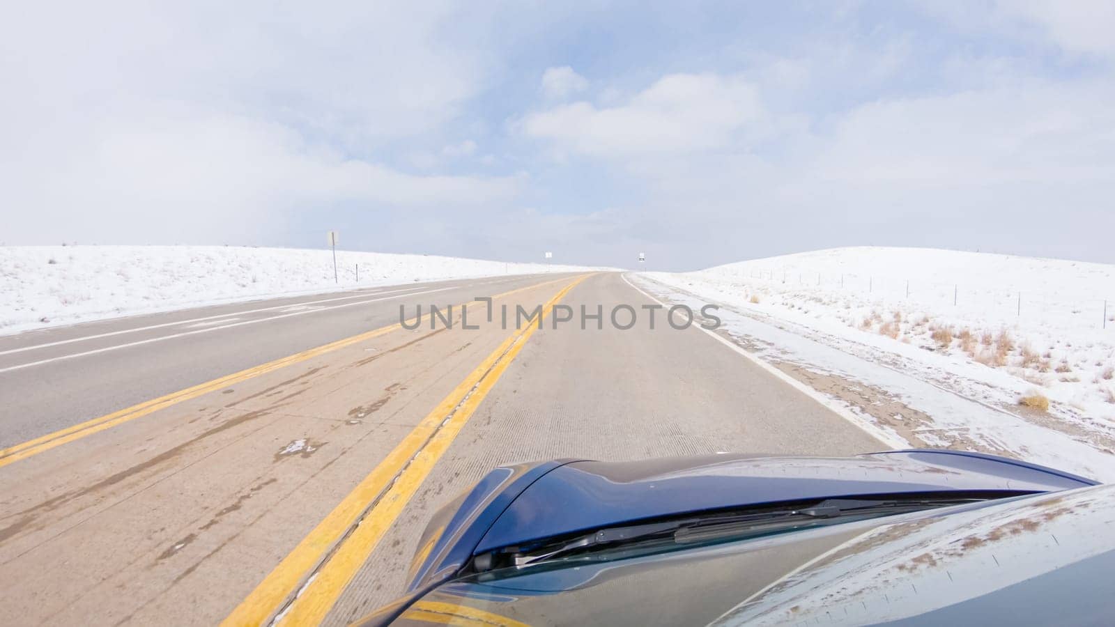 Navigating a frontage road post-winter storm offers a serene drive. The surrounding landscape, blanketed in snow, contributes to the peaceful and picturesque environment, enhancing the driving experience.