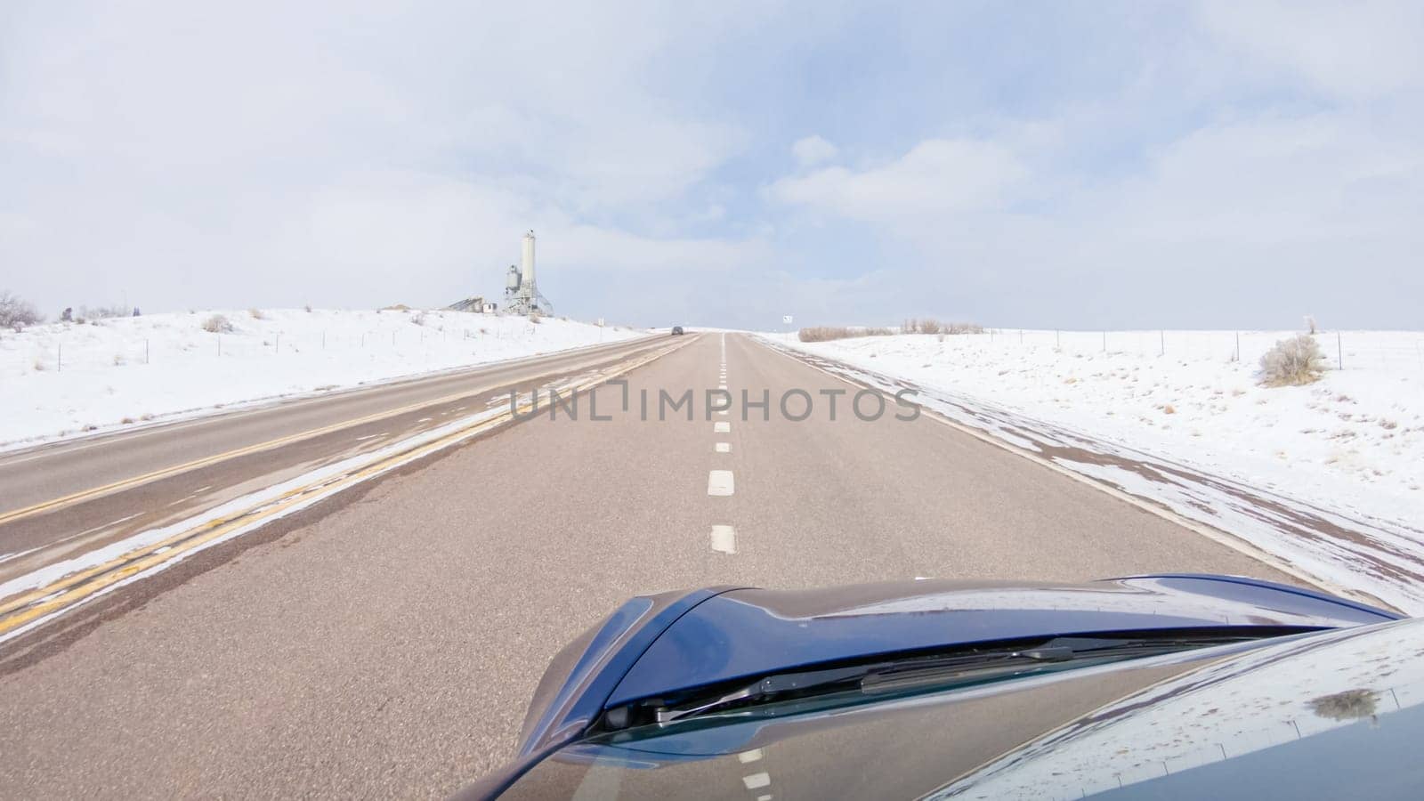 Navigating a frontage road post-winter storm offers a serene drive. The surrounding landscape, blanketed in snow, contributes to the peaceful and picturesque environment, enhancing the driving experience.