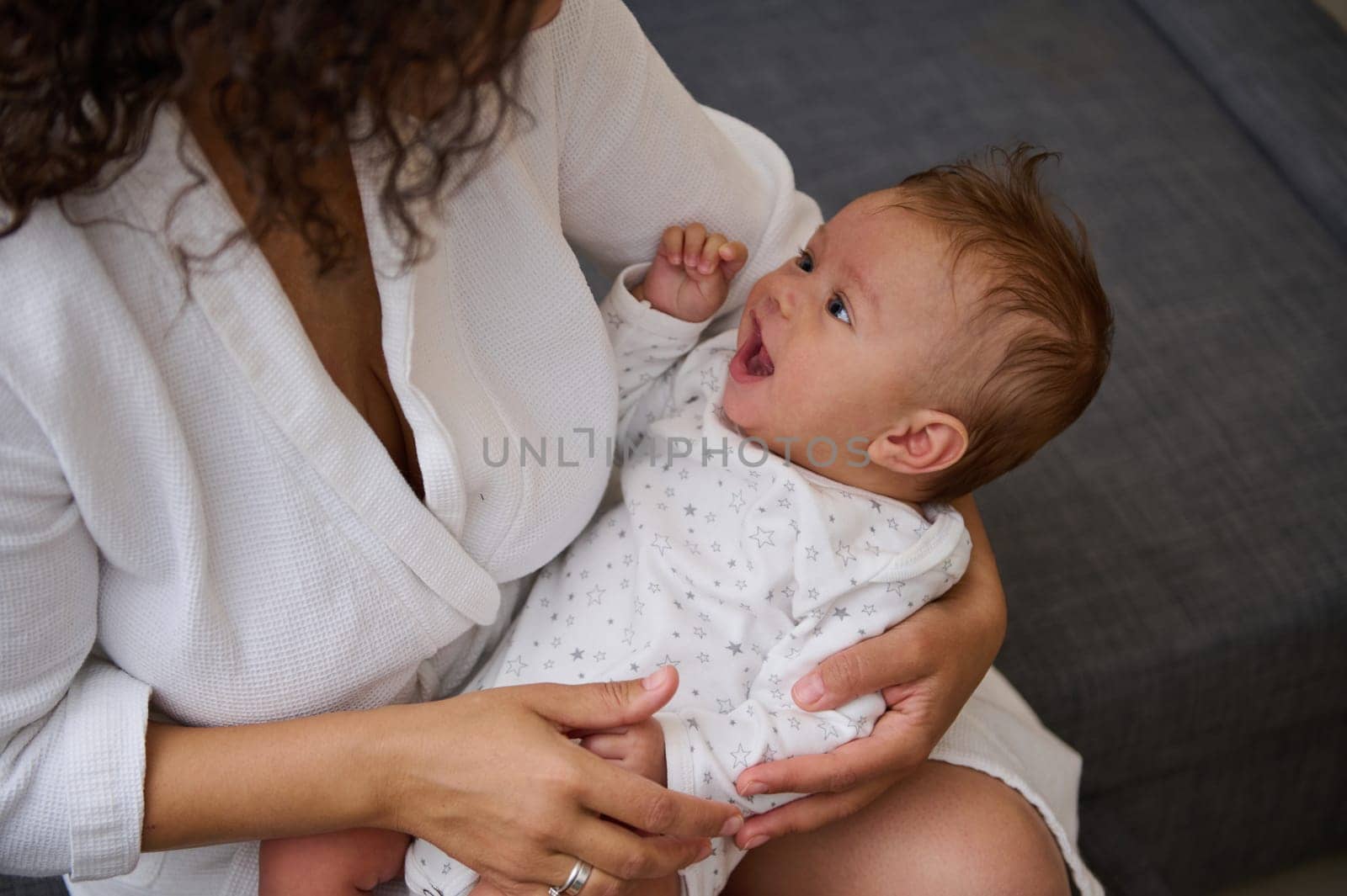 Close-up portrait of a cute baby boy smiling in the hands of his loving caring mother. Loving young mom holds her lovely baby boy, close in moment filled with tenderness with affection creating memory