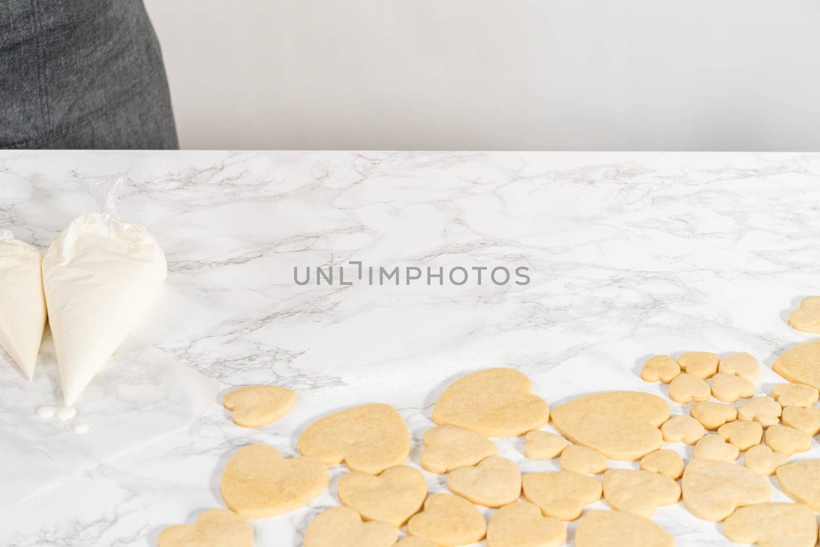 Decorating heart-shaped sugar cookies with pink and white royal icing for Valentine's Day.