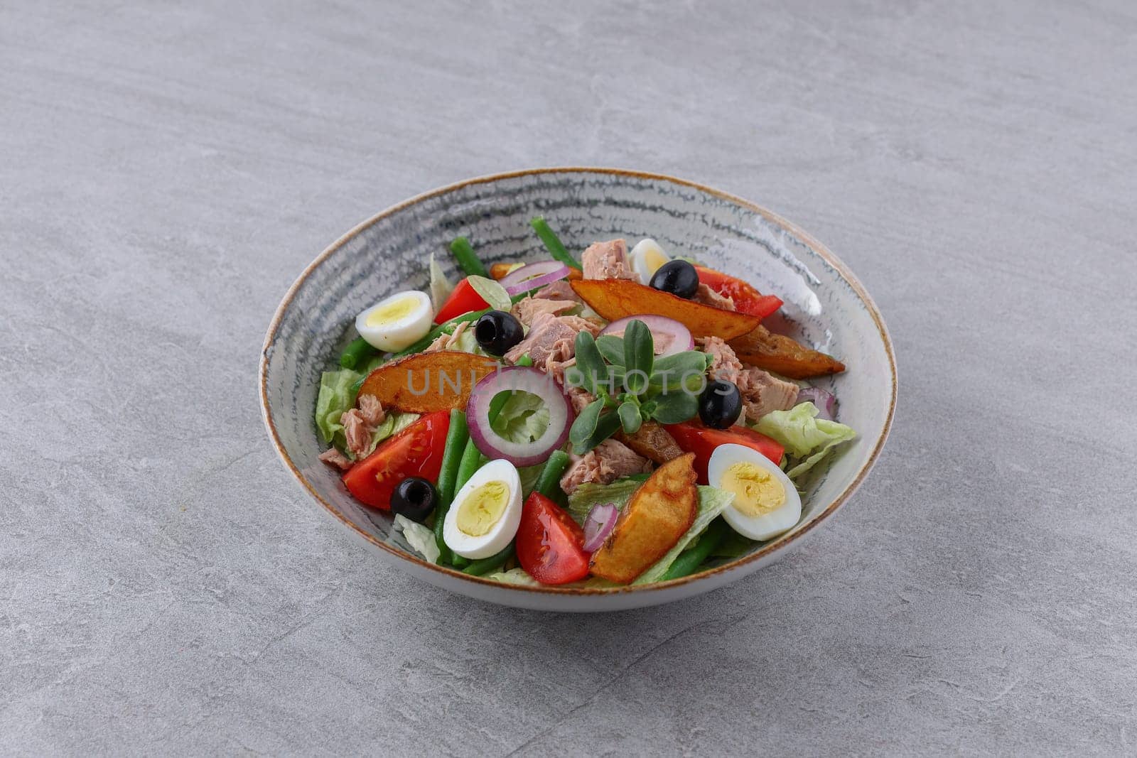 salad with tuna, quail eggs and baked potatoes on a stone background, studio food photography