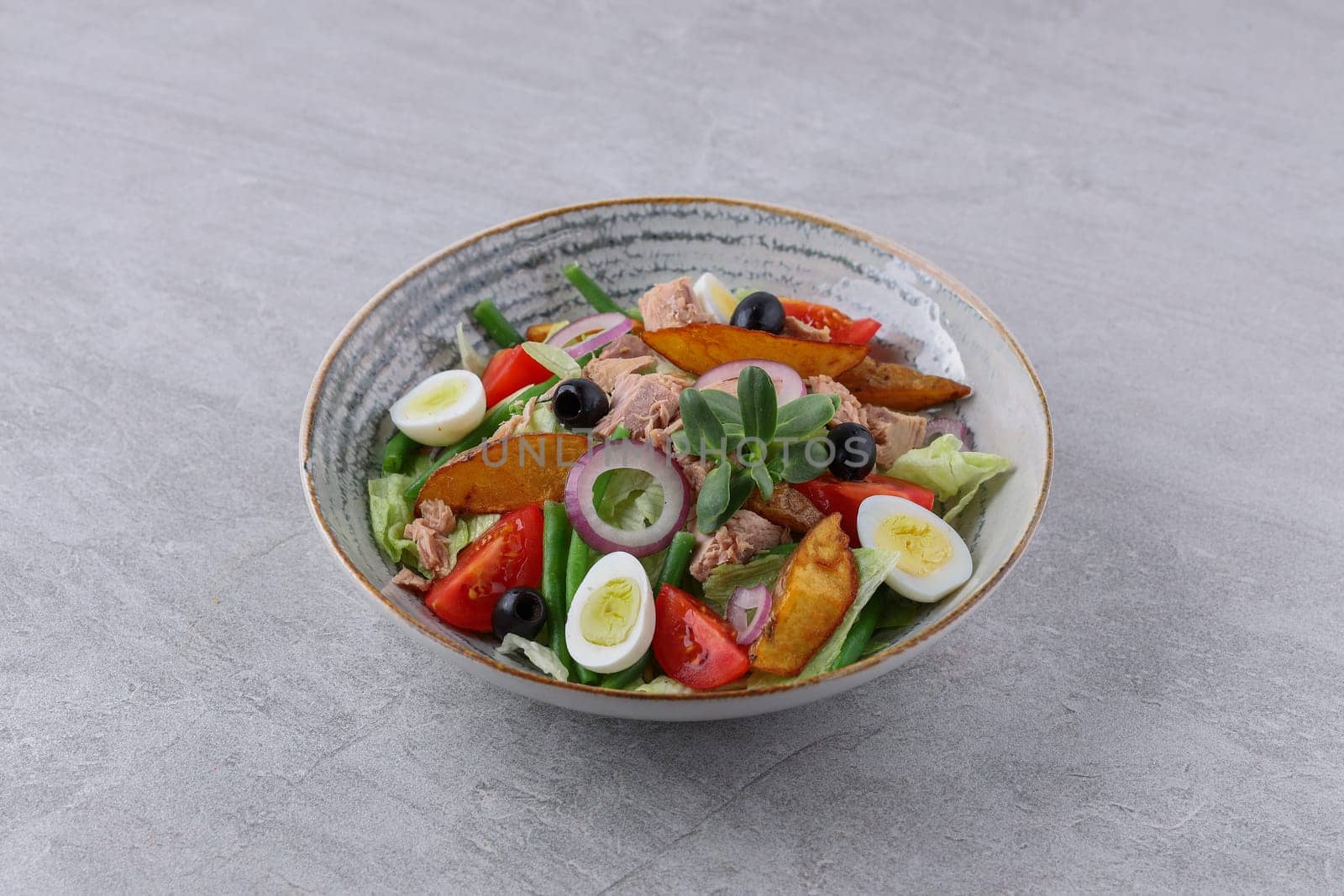 salad with tuna, quail eggs and baked potatoes on a stone background, studio food photography 2