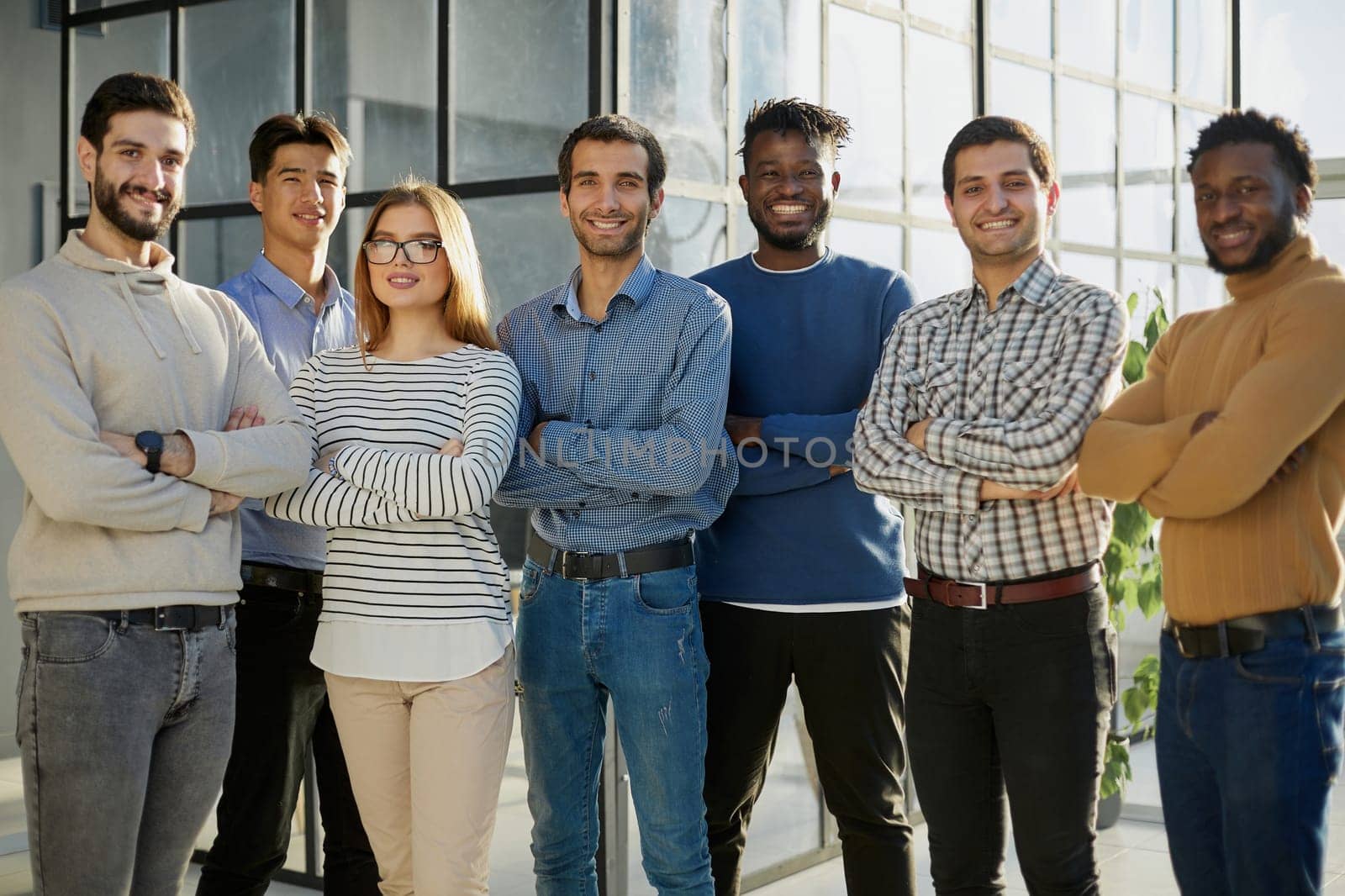 a group of business people of six people standing in the office looking at the camera in casual clothes
