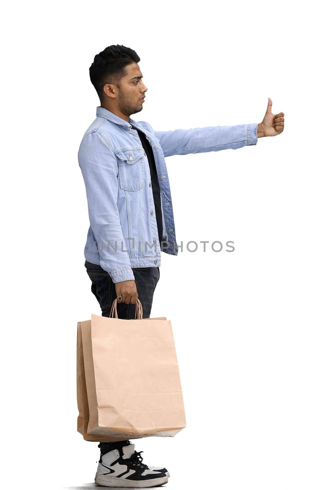 Man on a white background with shoppers show thumb up, in profile.