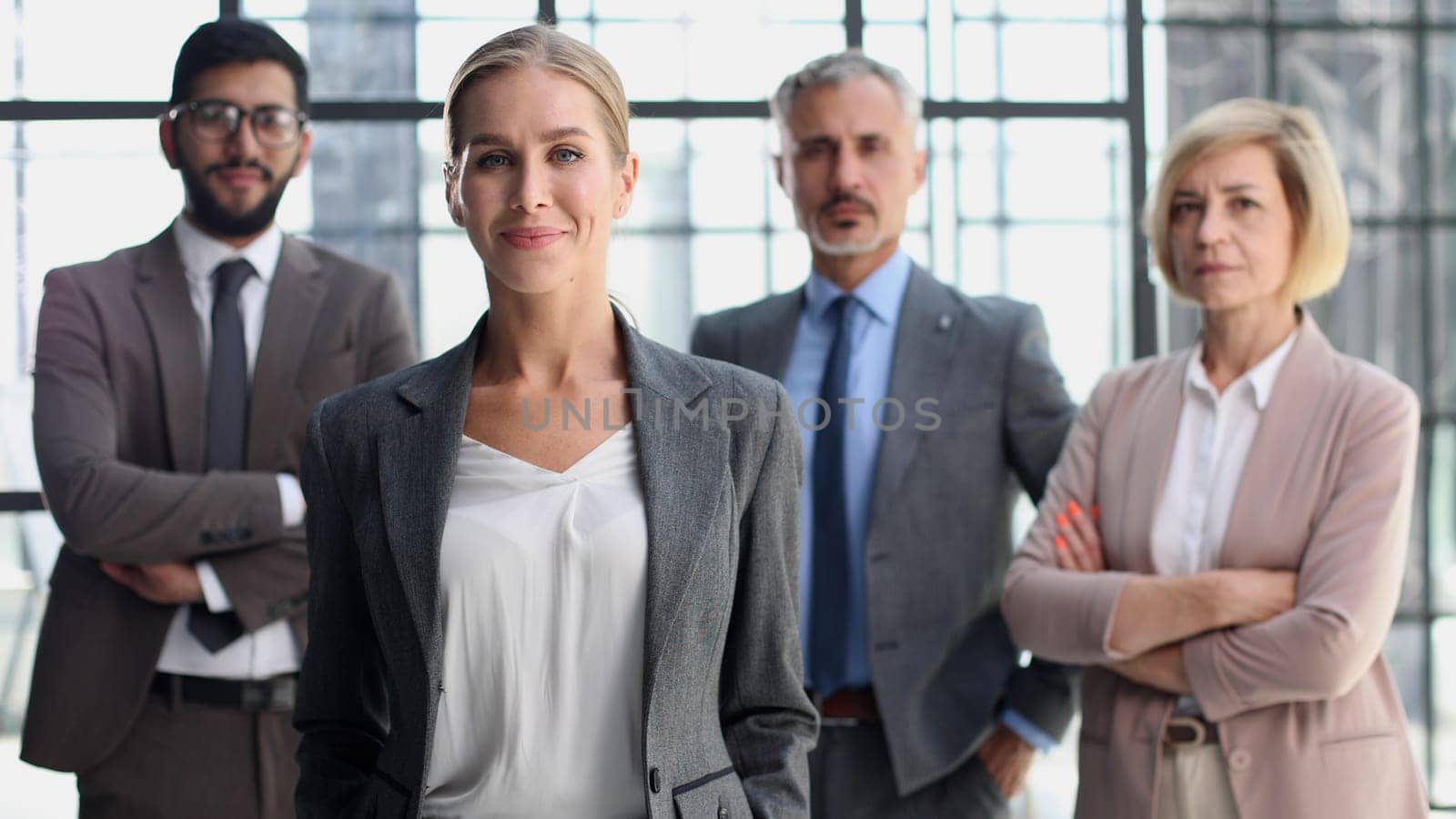Confident leader. Attractive young woman holding arms crossed and smiling while group of people standing behind her