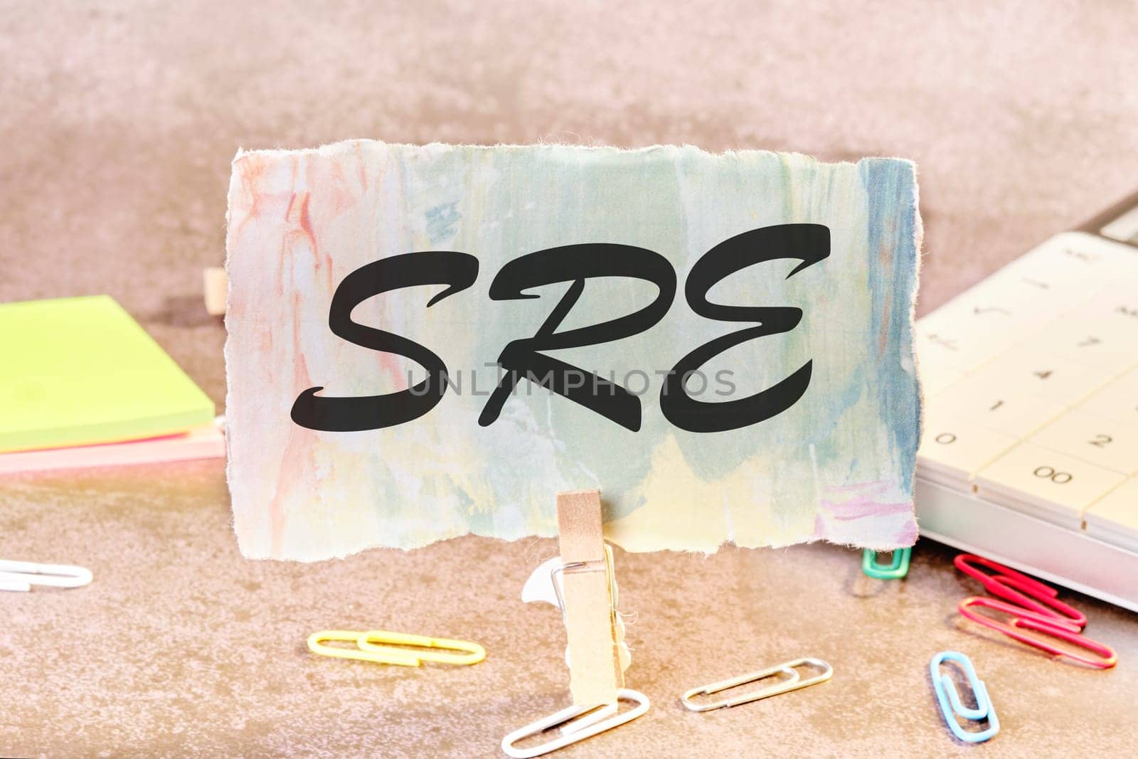 SRE. Site Reliability Engineering text on a piece of paper on the table with a clothespin clamped