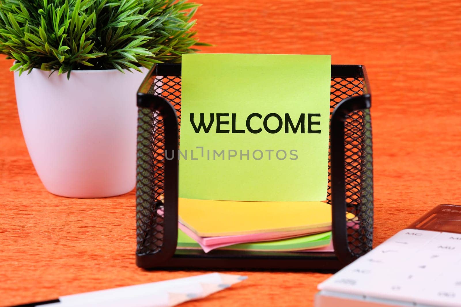 Business Concept. Welcome text written on a green sticker next to office supplies on an orange background