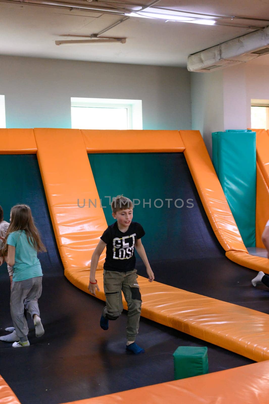 Ivano-Frankivsk, Ukraine June 7, 2023: A boy jumps on a trampoline in the playroom, big trampolines in the playhouse.
