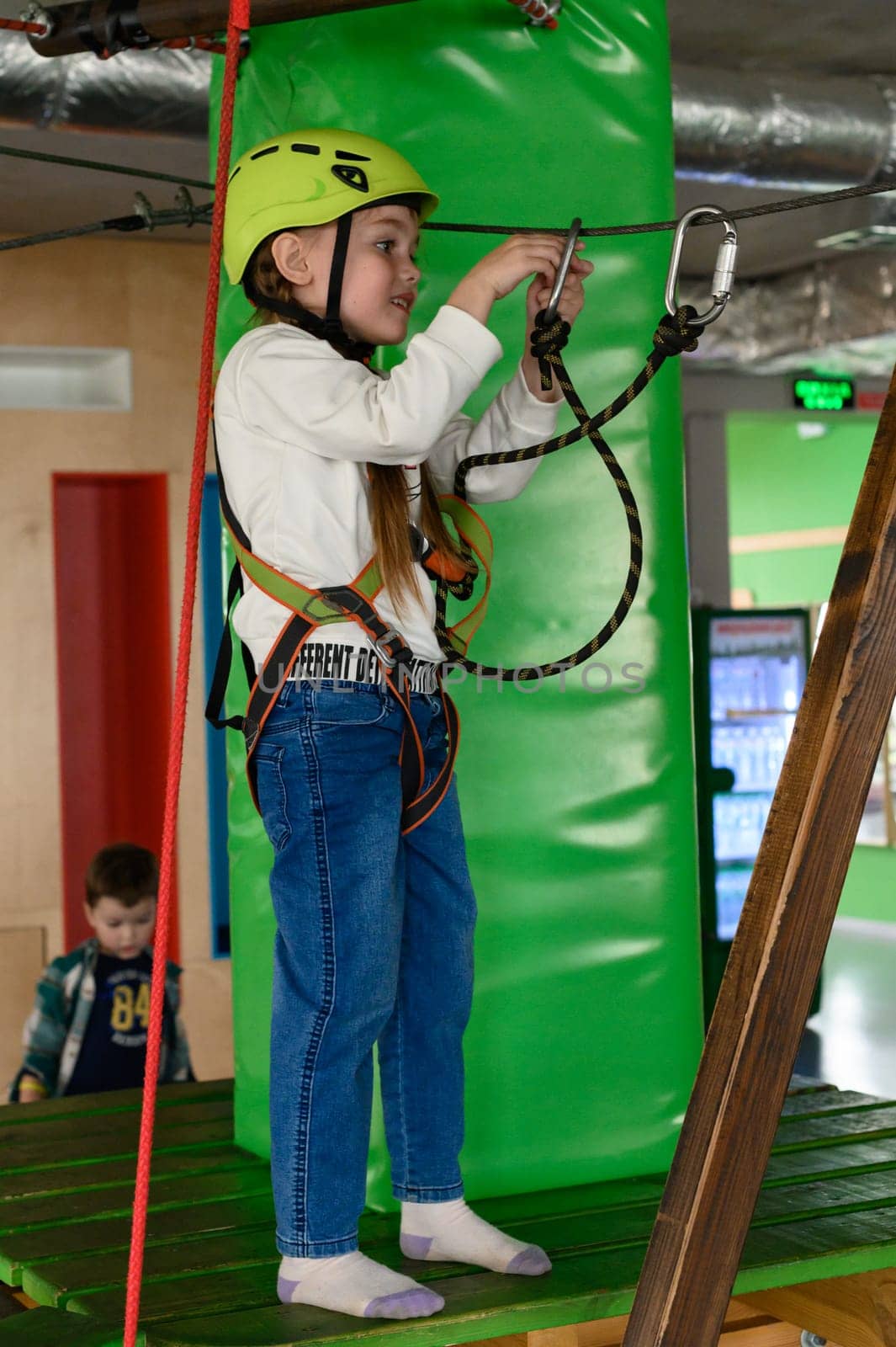 Ivano-Frankivsk, Ukraine June 7, 2023:A little girl refastens a carabiner to another cable to go through another section of the cableway, active recreation for children.