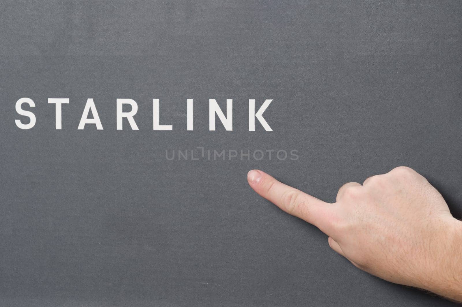 Ivano-Frankivsk, Ukraine December 2, 2023: Starlink antenna box with logo, man pointing with index finger to SpaceX company logo. by Niko_Cingaryuk