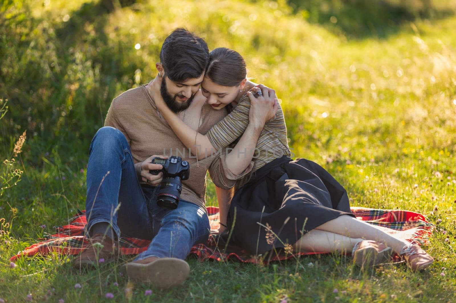 young couple looking at photos on a camera by zokov
