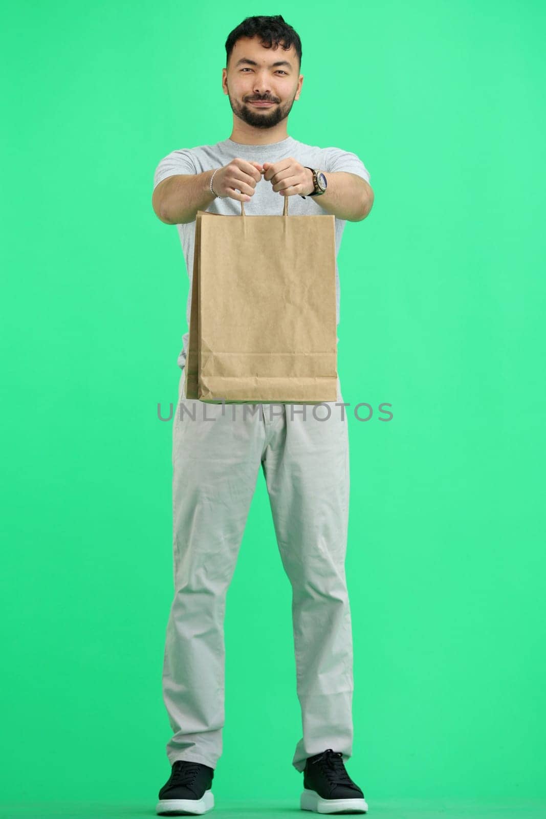 A man, full-length, on a green background, with bags.
