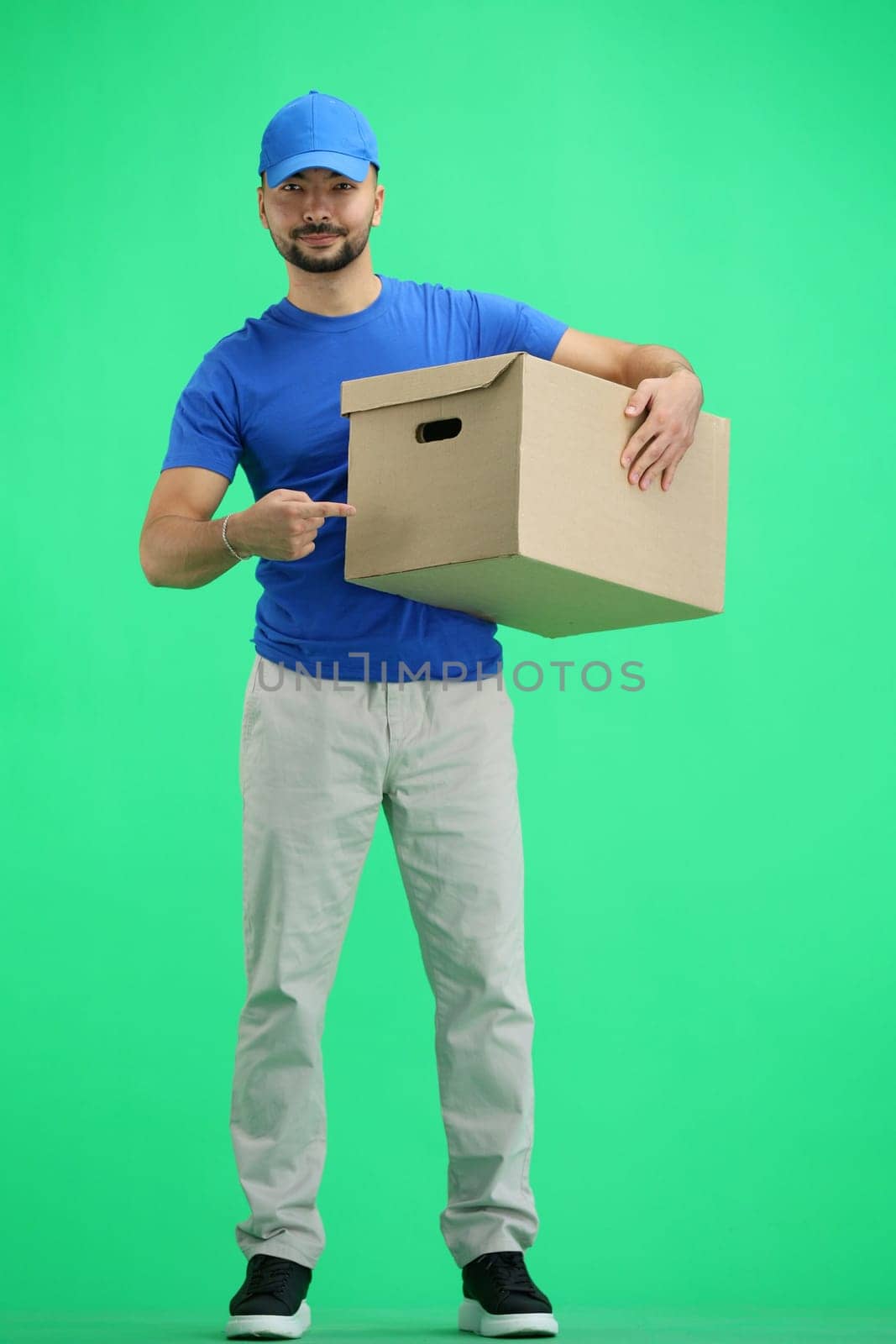 The deliveryman, in full height, on a green background, points to the box by Prosto
