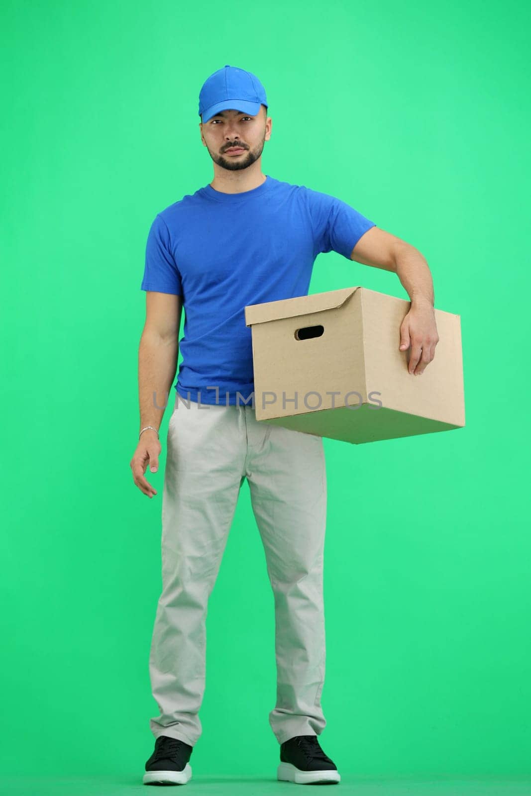 The deliveryman, full-length, on a green background, with a box.
