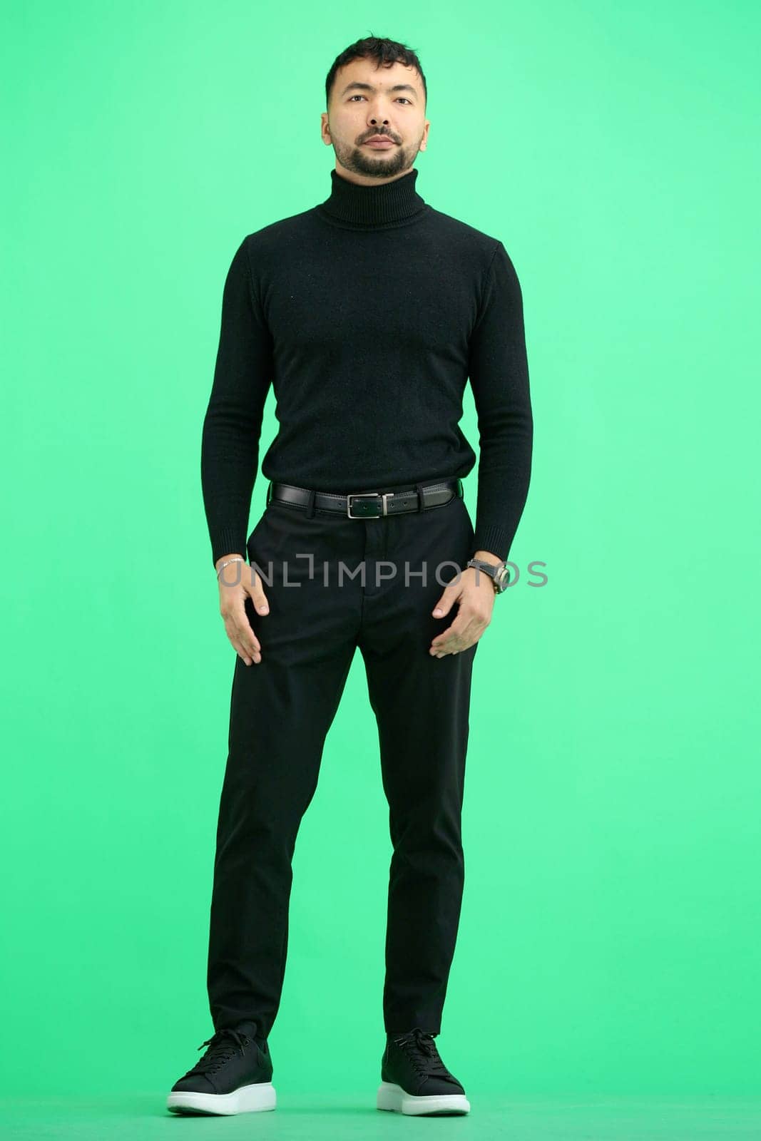 A man, on a green background, in full height.