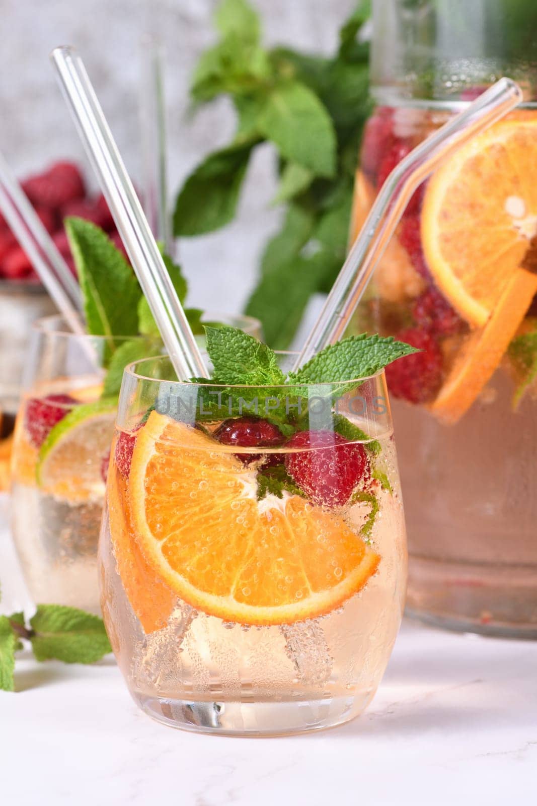 Summer Sangria cocktail or lemonade with raspberry, orange and mint. Refreshing organic non-alcoholic, Detox vitaminized healthy drink, fruit in a in a glass. Quench your thirst on a hot day.