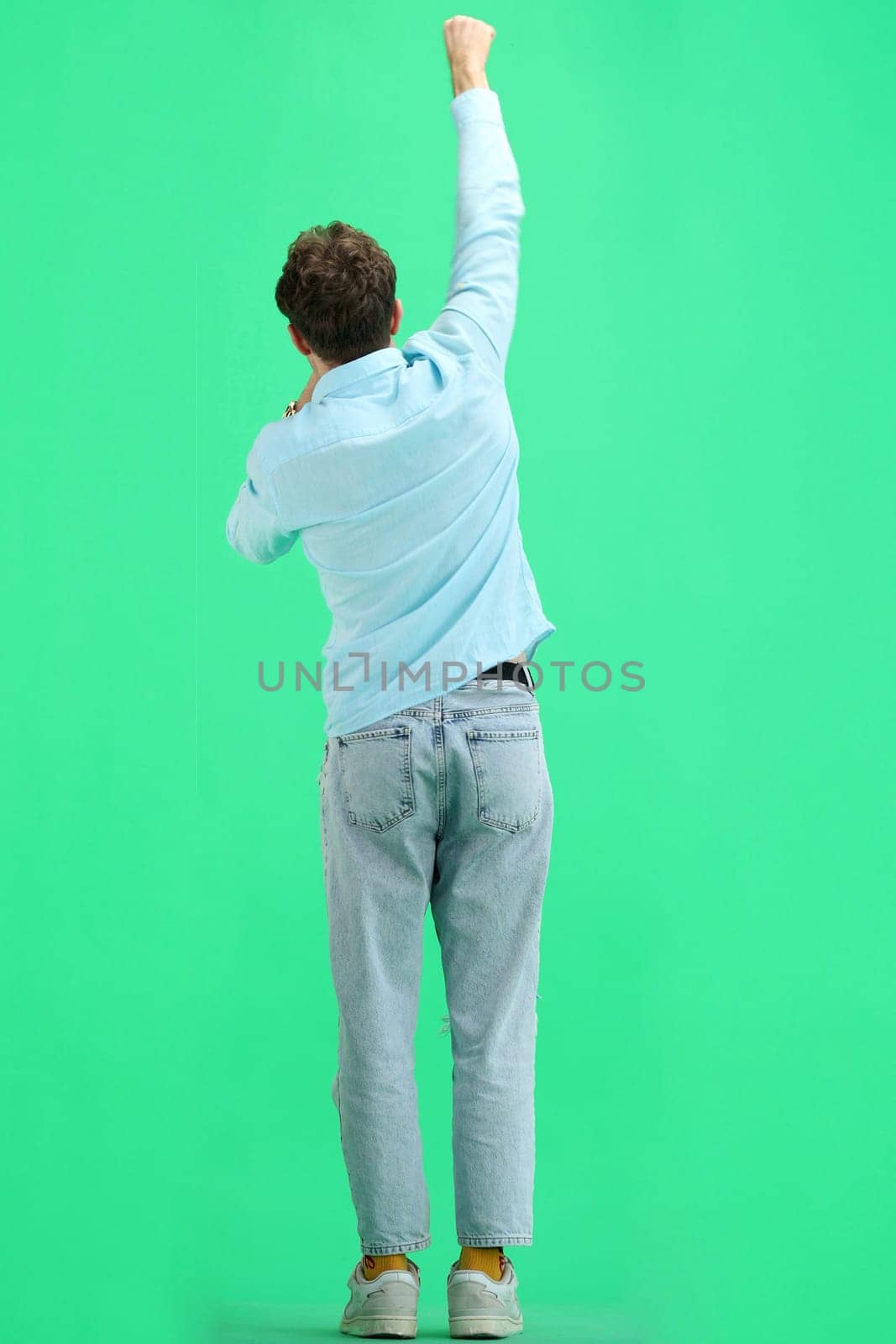 A man, on a green background, in full height, rejoices.