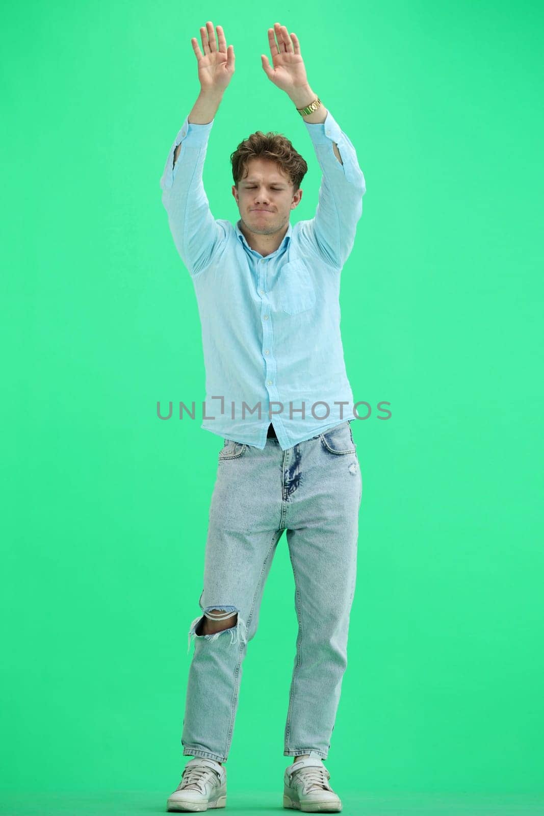A man, on a green background, in full height, dancing.