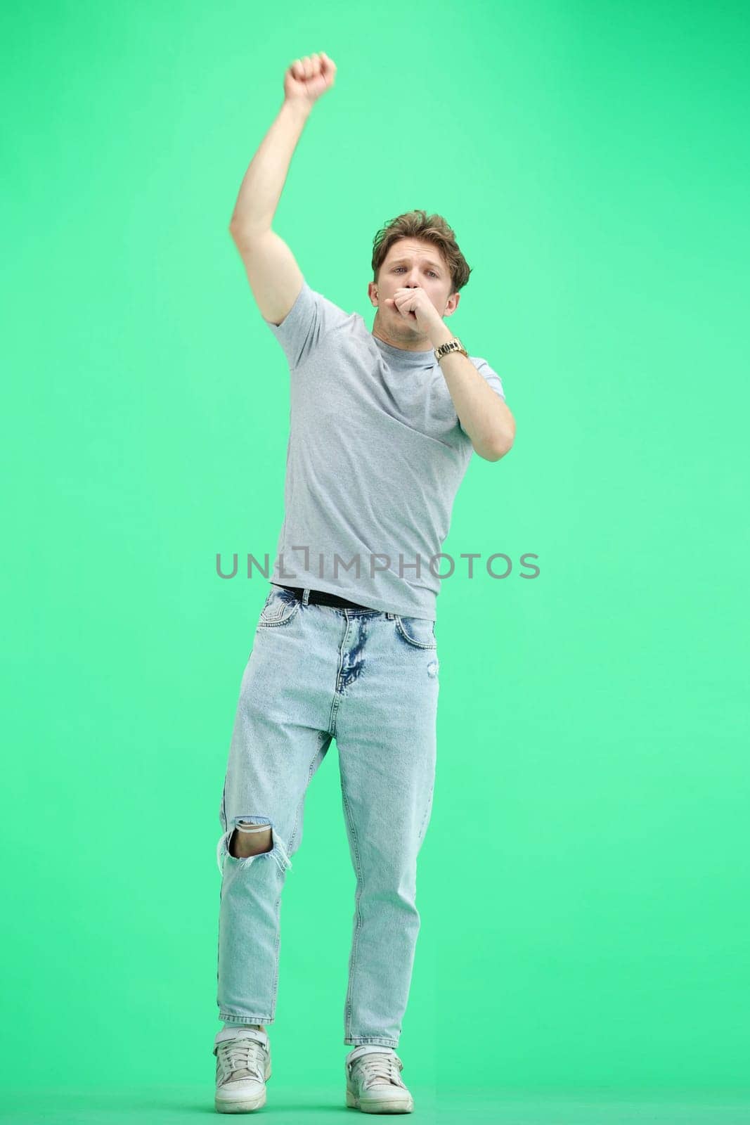 A man, on a green background, in full height, rejoices.