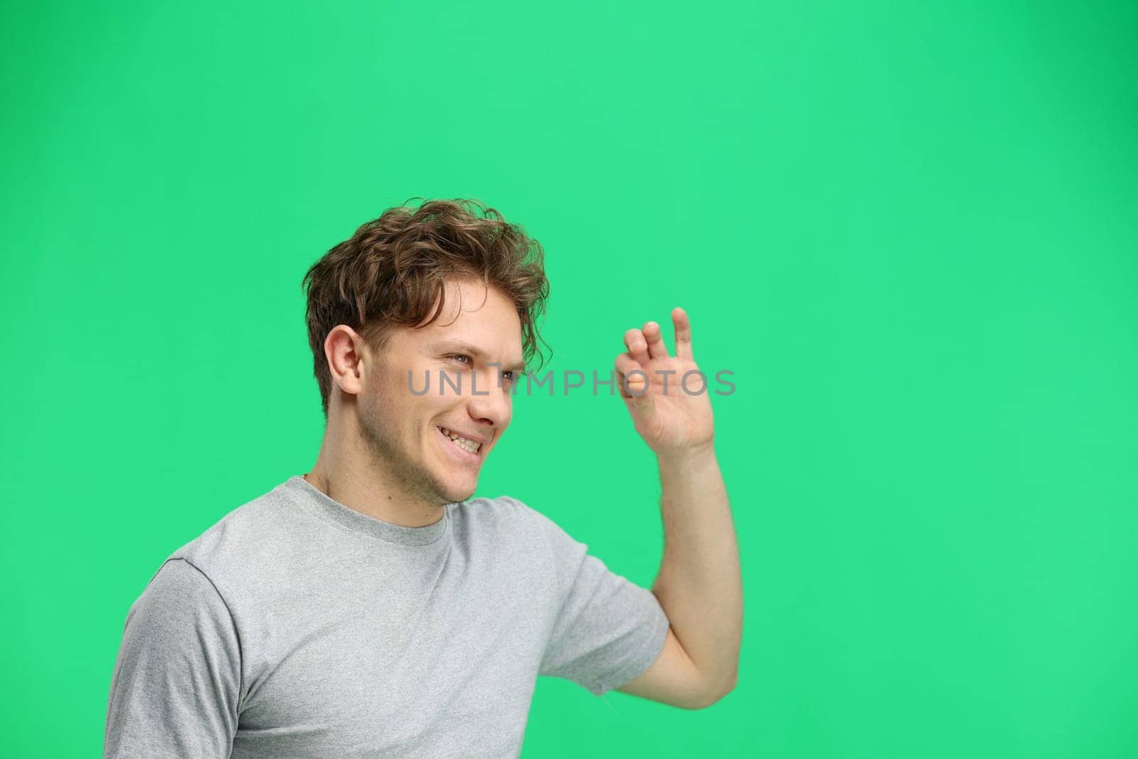 A man, on a green background, in close-up, shows an ok sign.