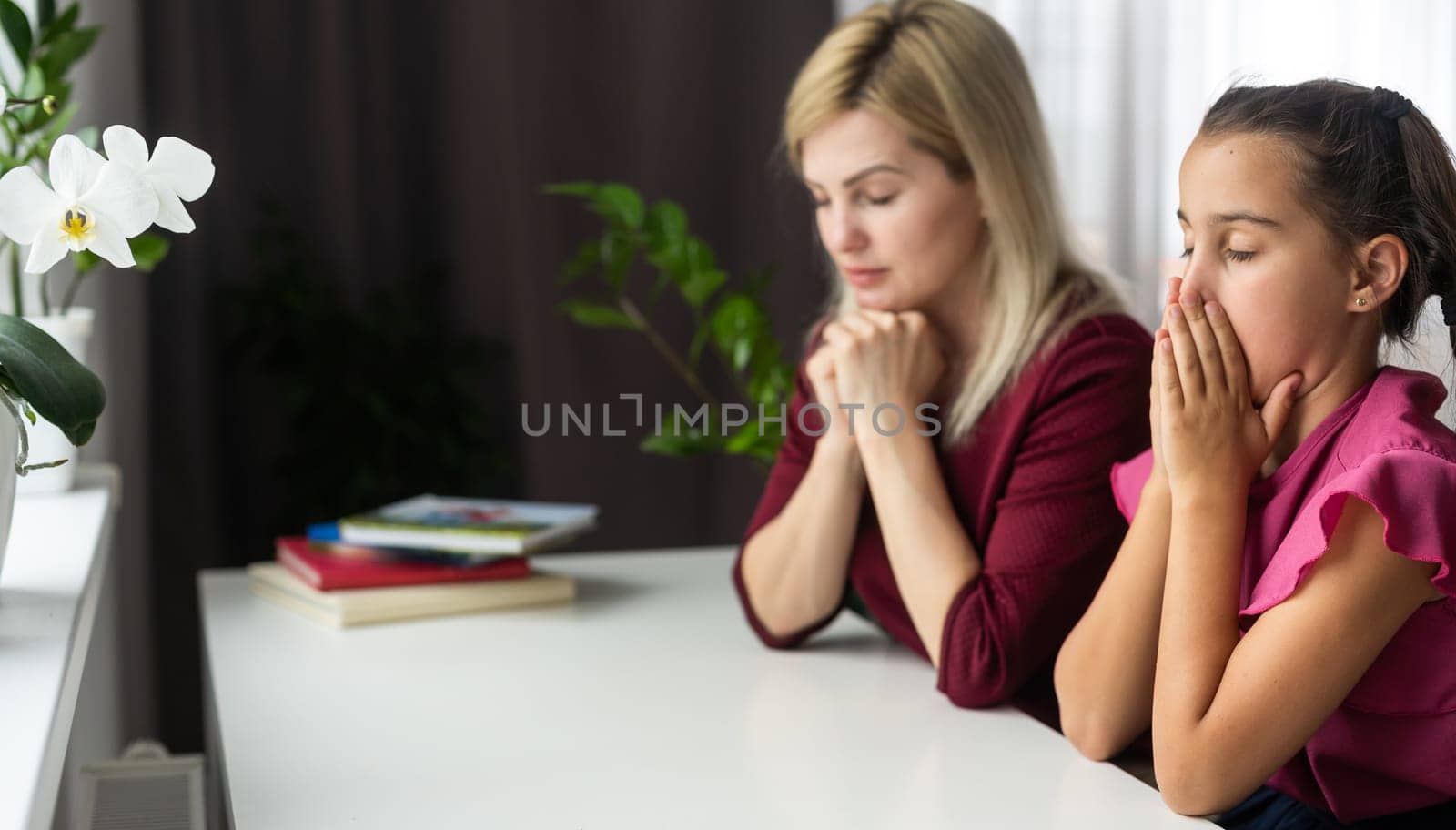 Religious Christian girl praying with her mother indoors by Andelov13