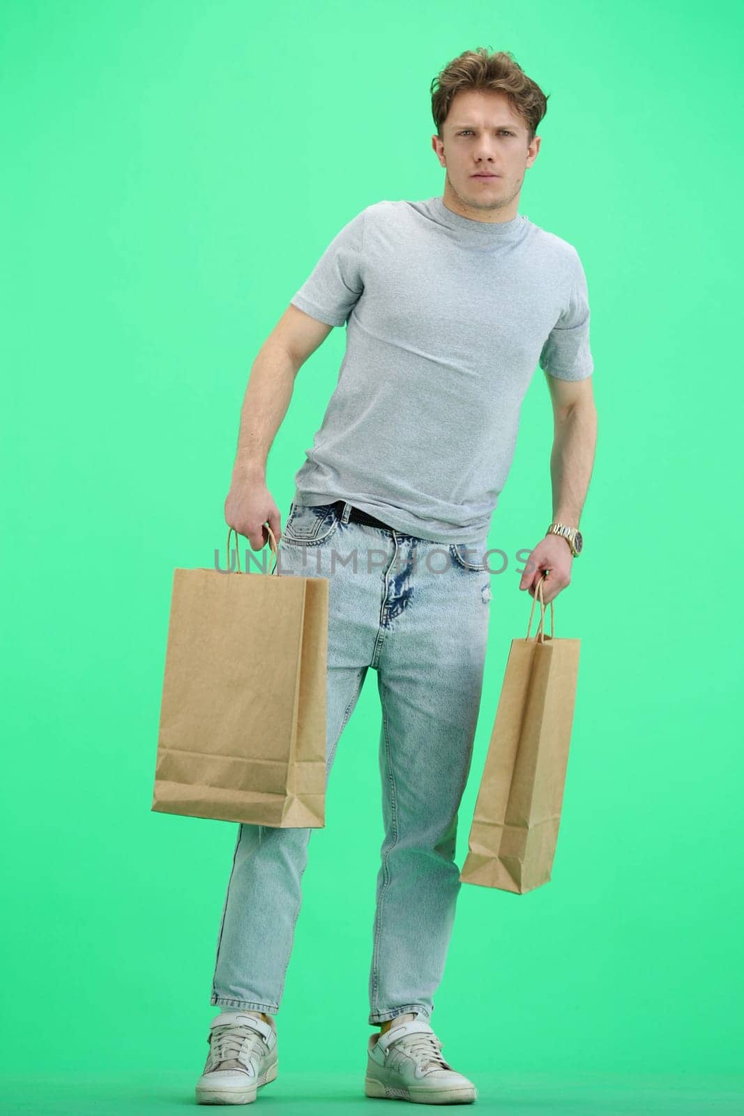 Man, on a green background, full-length, with bags by Prosto