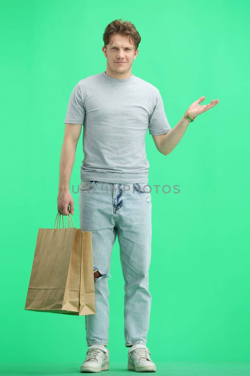 A man, full-length, on a green background, with bags by Prosto