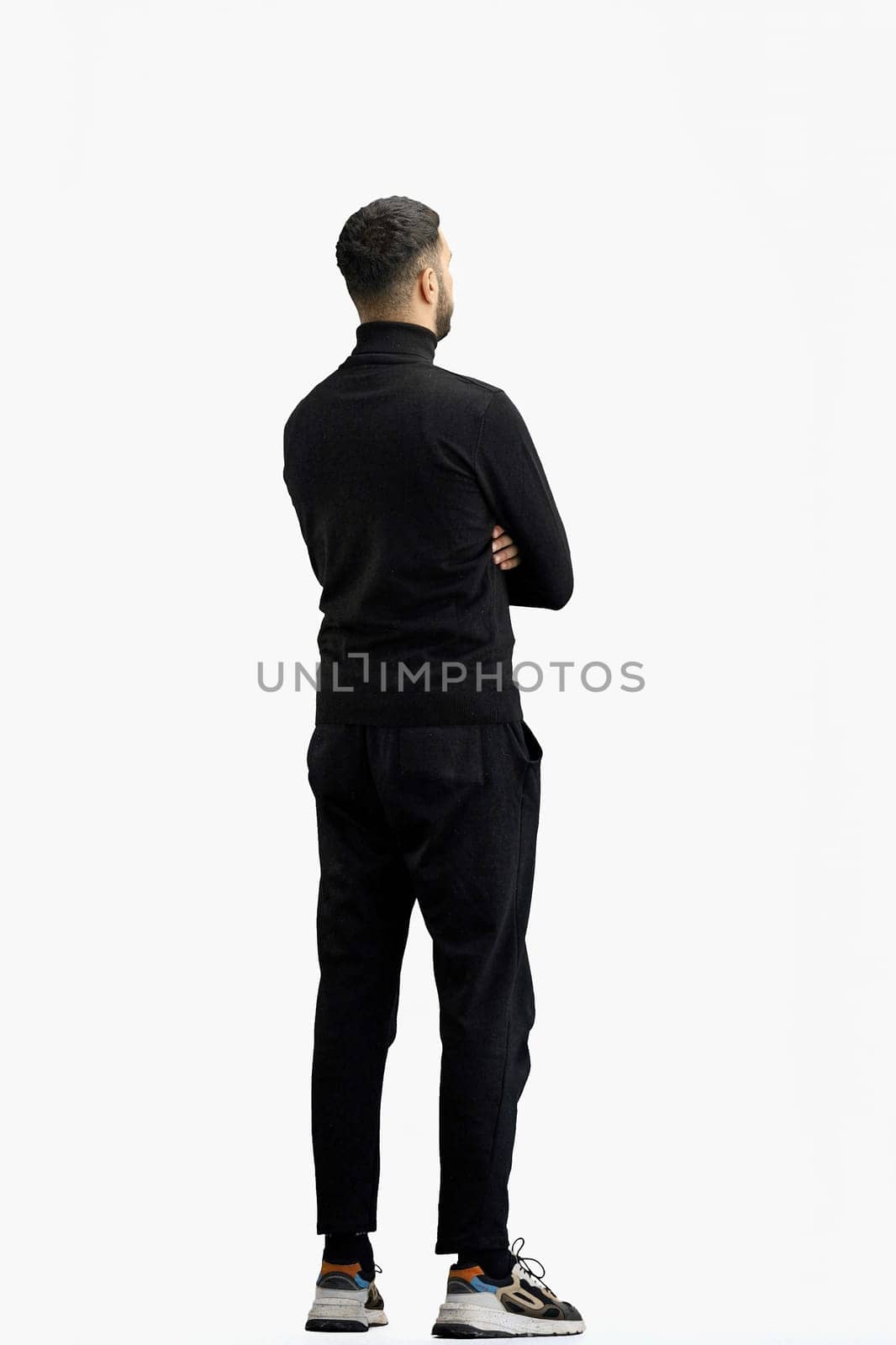A man, full-length, on a white background, crossed his arms.