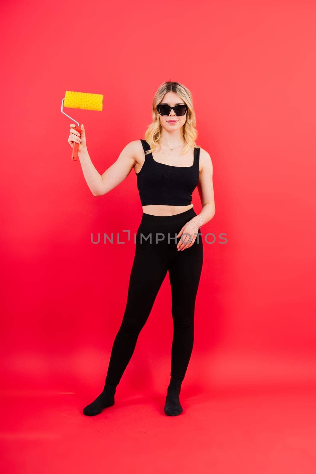 Young woman with roller brush on red white backgrounds Instruments accessories for renovation room