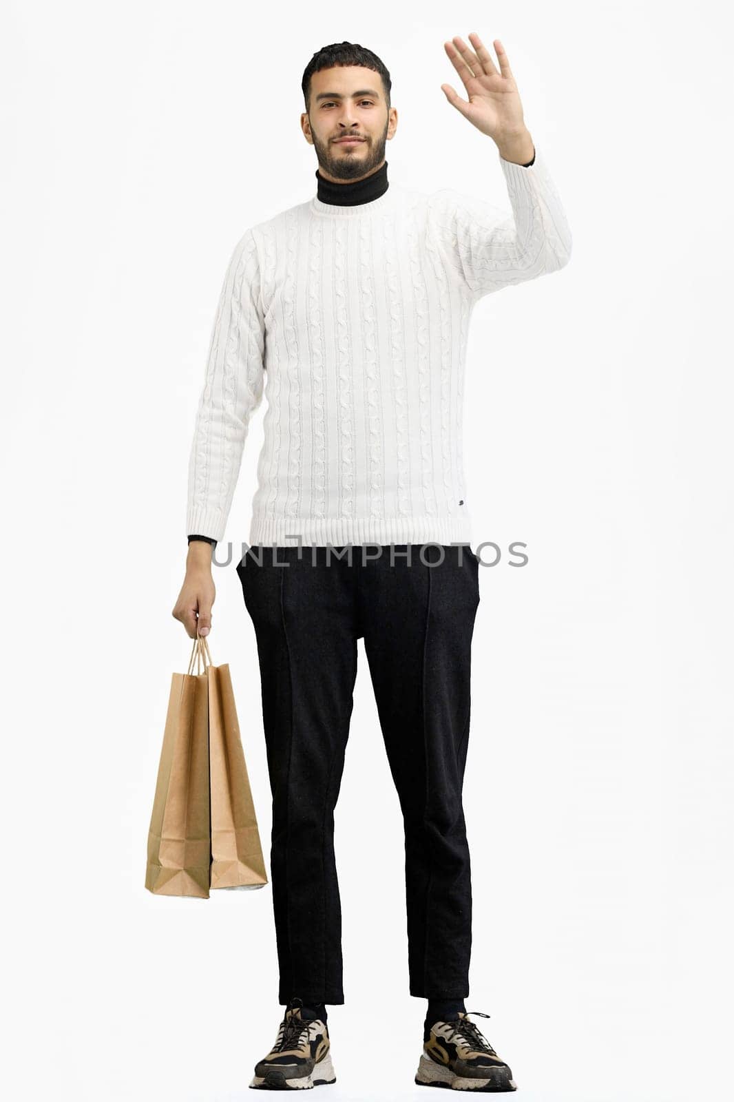 A man, full-length, on a white background, with bags, waving his hand.