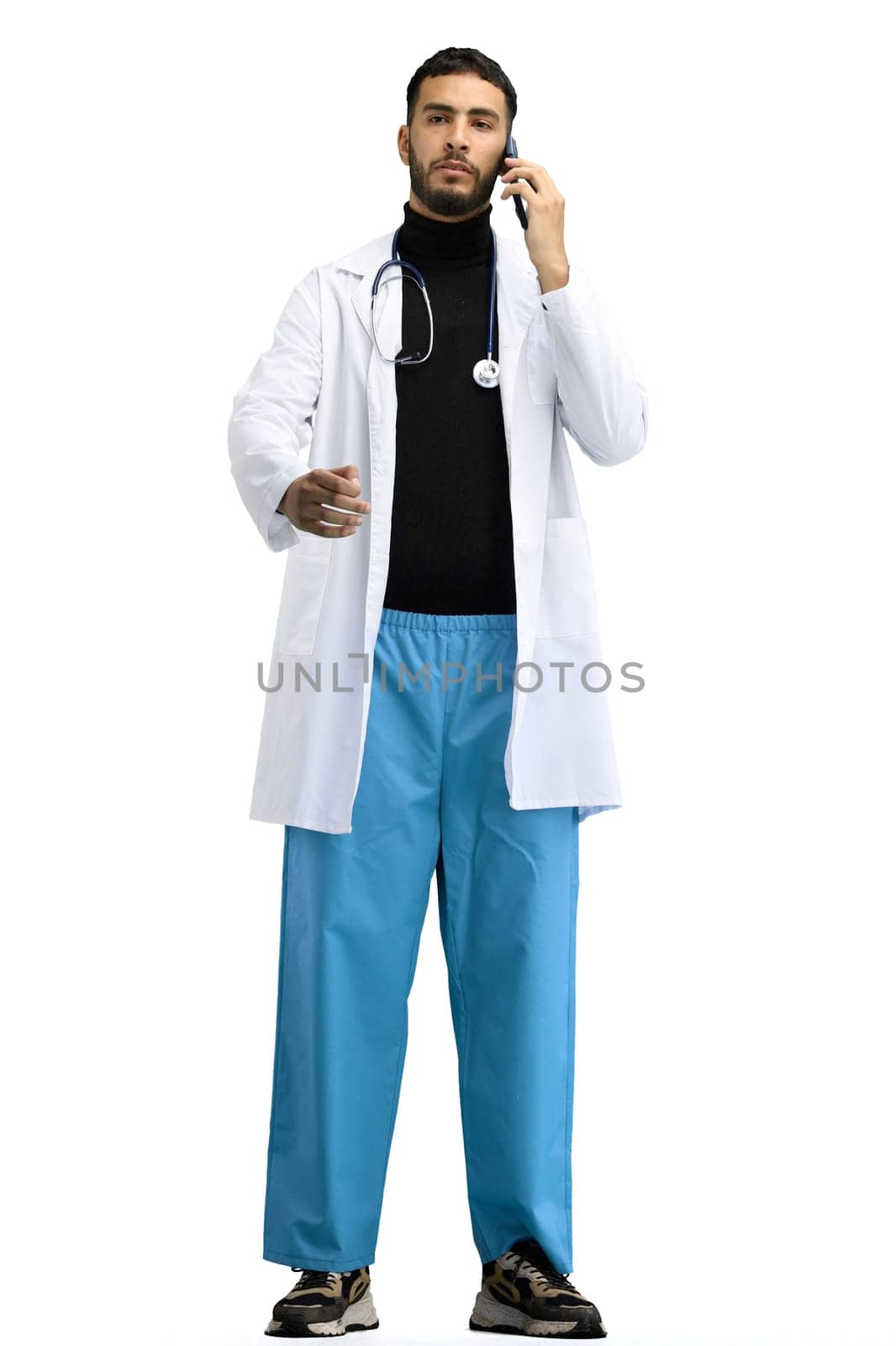 The doctor, in full height, on a white background, uses a stethoscope.