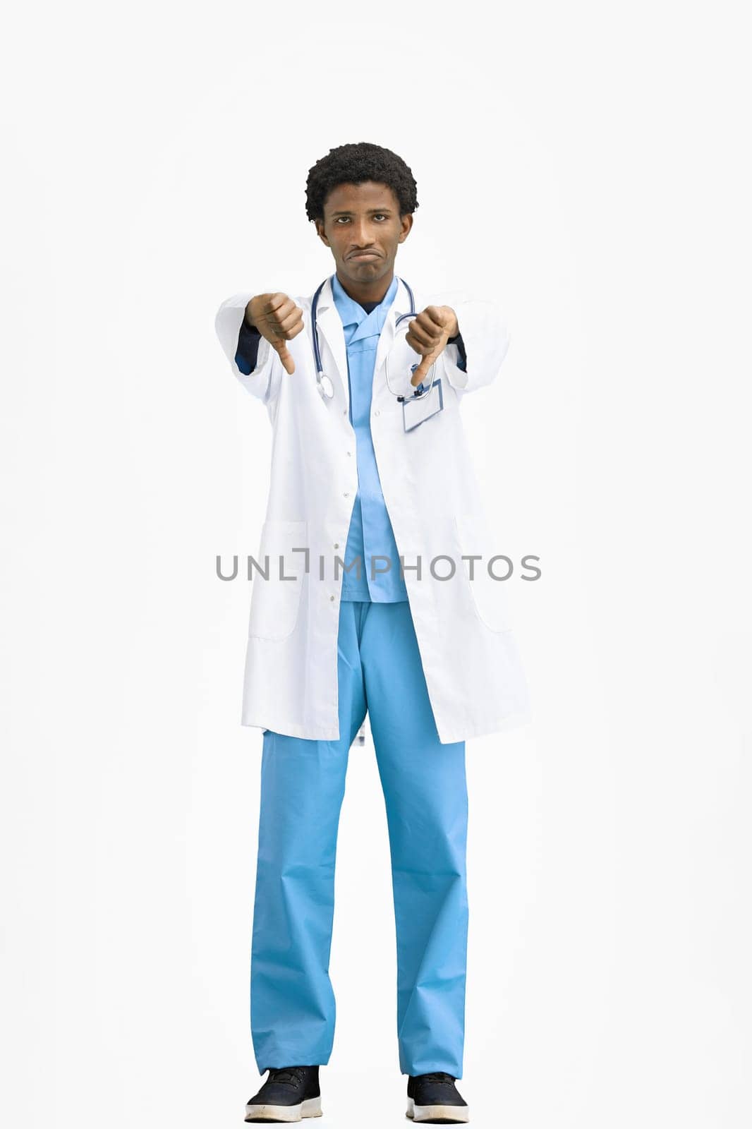 The doctor, in full height, on a white background, shows his thumbs down.
