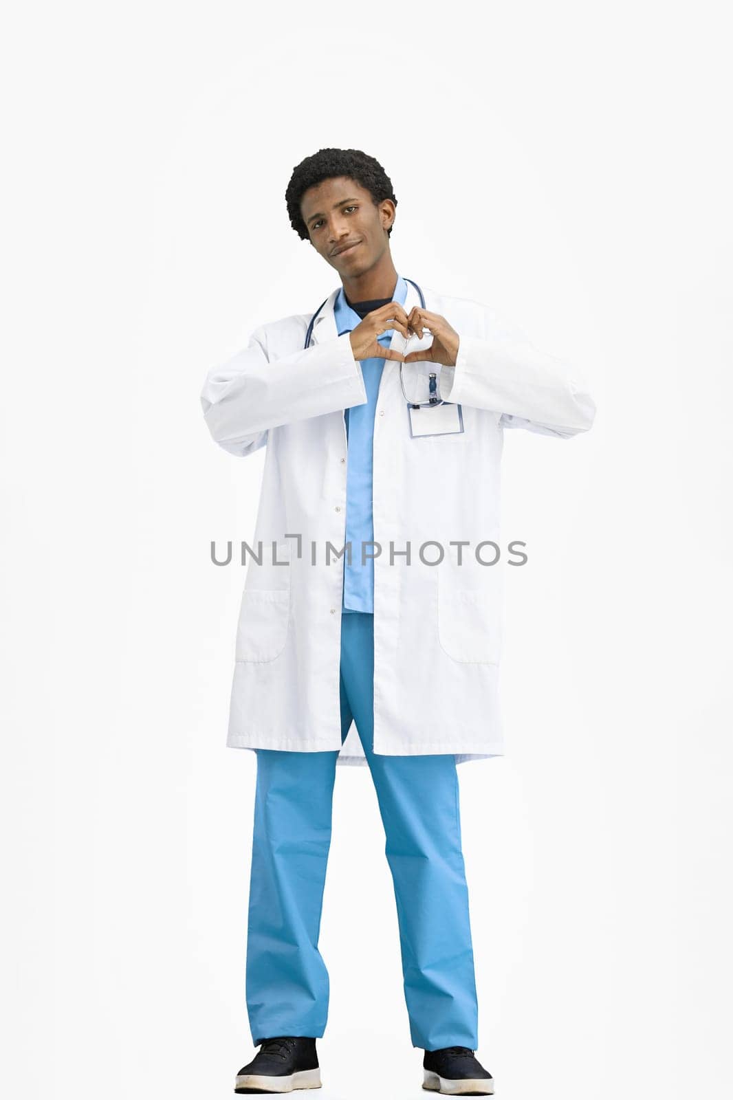 The doctor, in full height, on a white background, shows the heart.