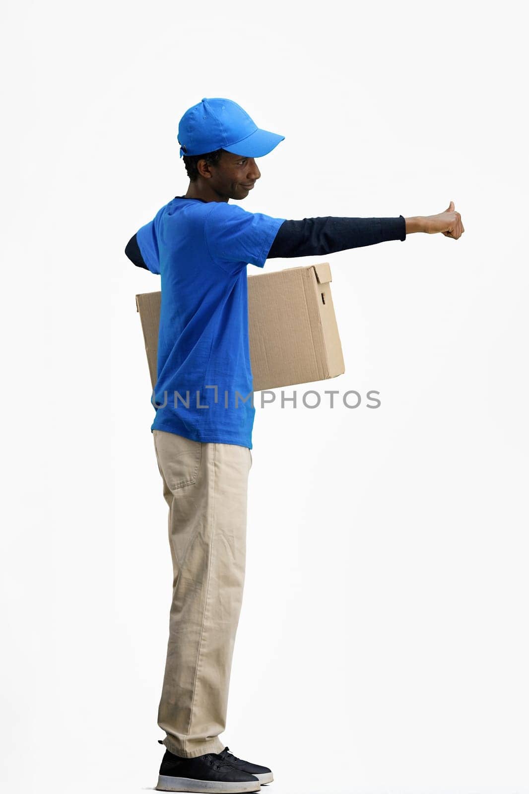The deliveryman, in full height, on a white background, with a box, shows a thumbs up.