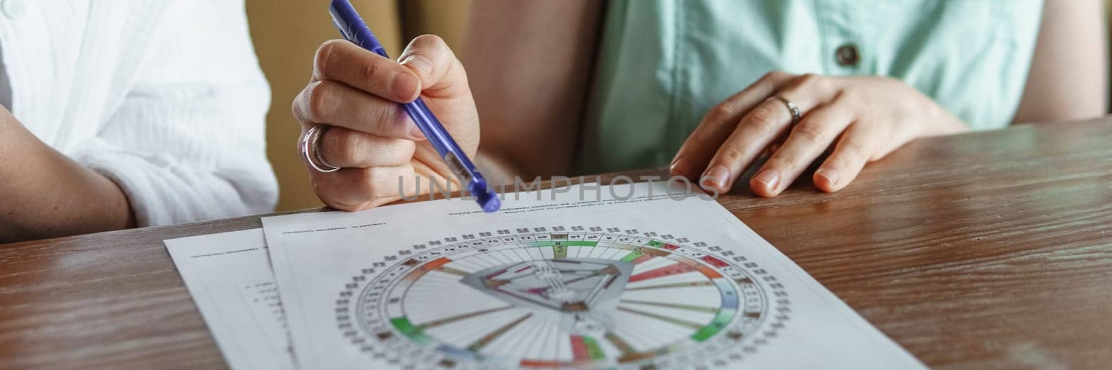 Tver, Russia - August 2, 2021. A woman in a cafe at a table is studying the design of a person. The concept of studying esoteric sciences. A bodigraph or a map of a person on an A4 sheet