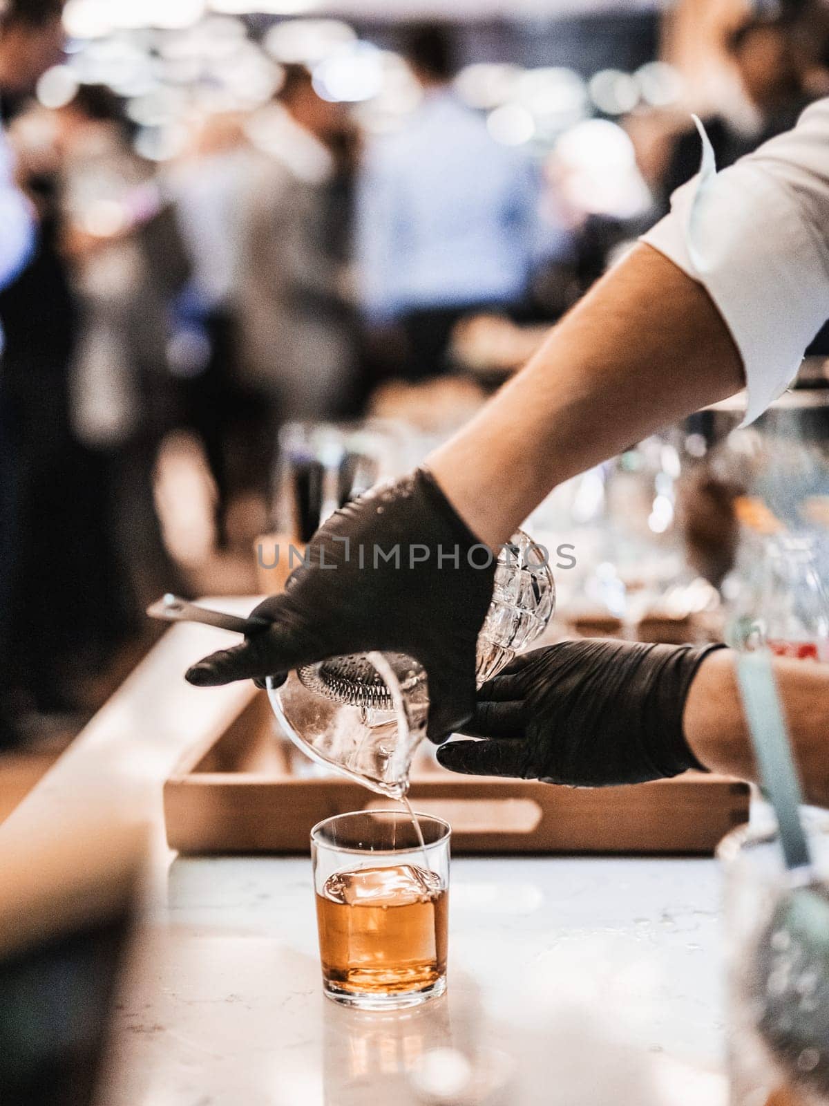 Expert barman is making cocktail at business banquet event in hotel conference center. Blurred businesspeople at banquet event business meeting event in the background by kasto